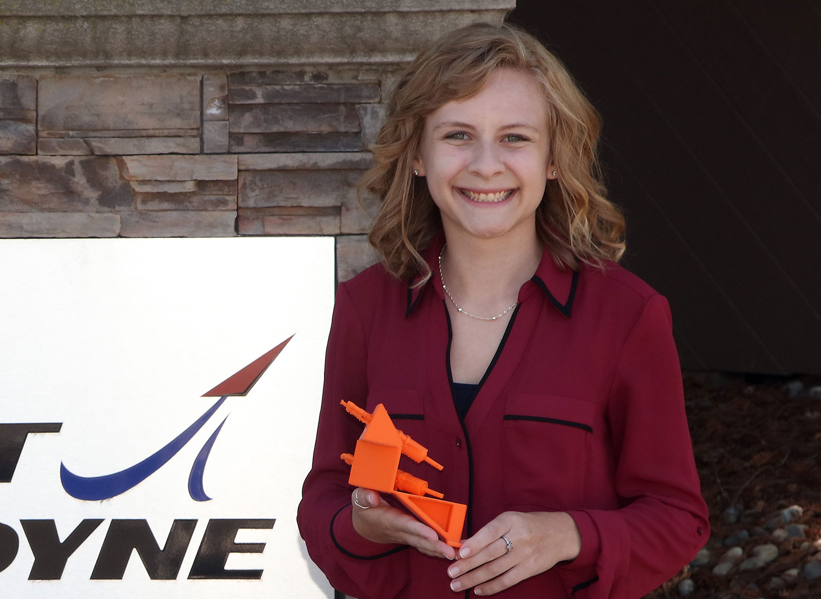 A photo of Sac State student Elizabeth Gabler holding a model of the bracket she designed for Aerojet Rockeydyne