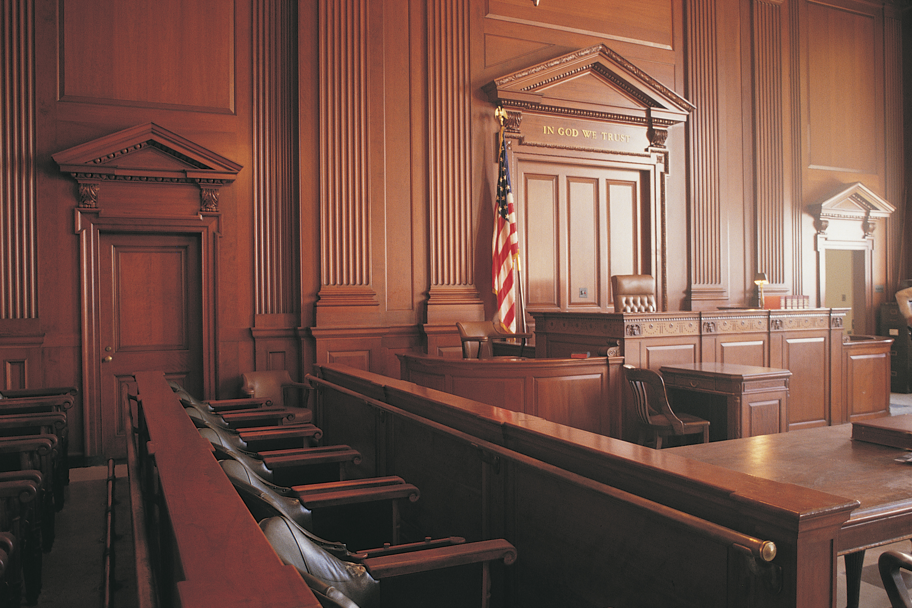 A photo of the dais in an empty courtroom, from the perspective of the jurors box