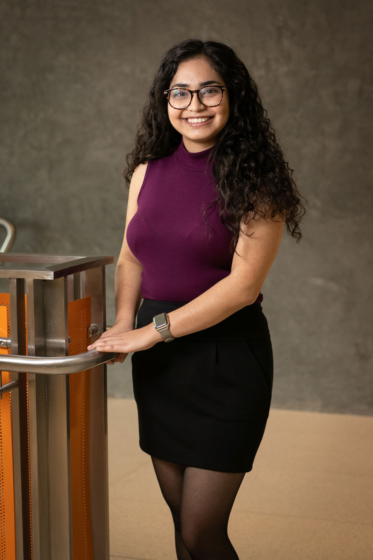A photo of Jacqueline Avina Espinoza, in a photo studio, smiling