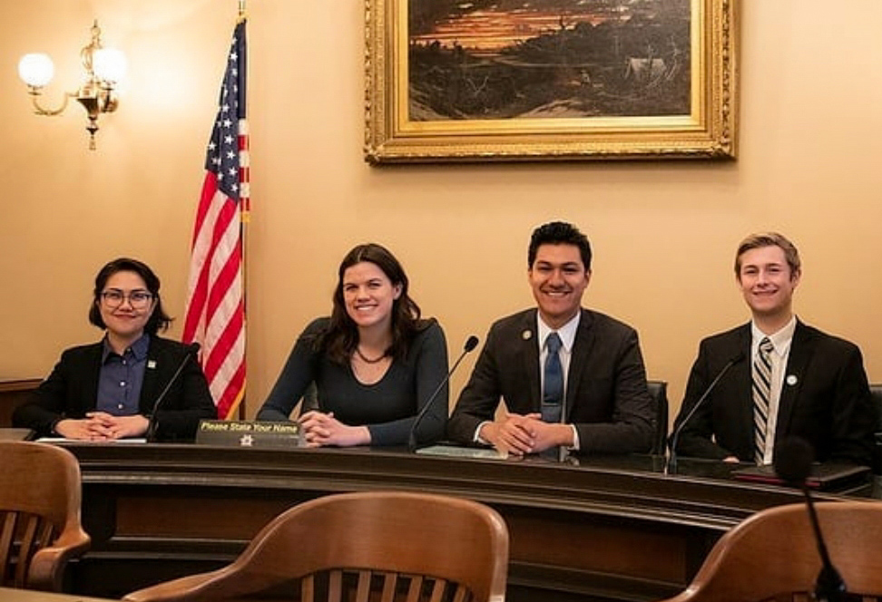 Four ASI leaders sitting at a table, with an American flag in the background