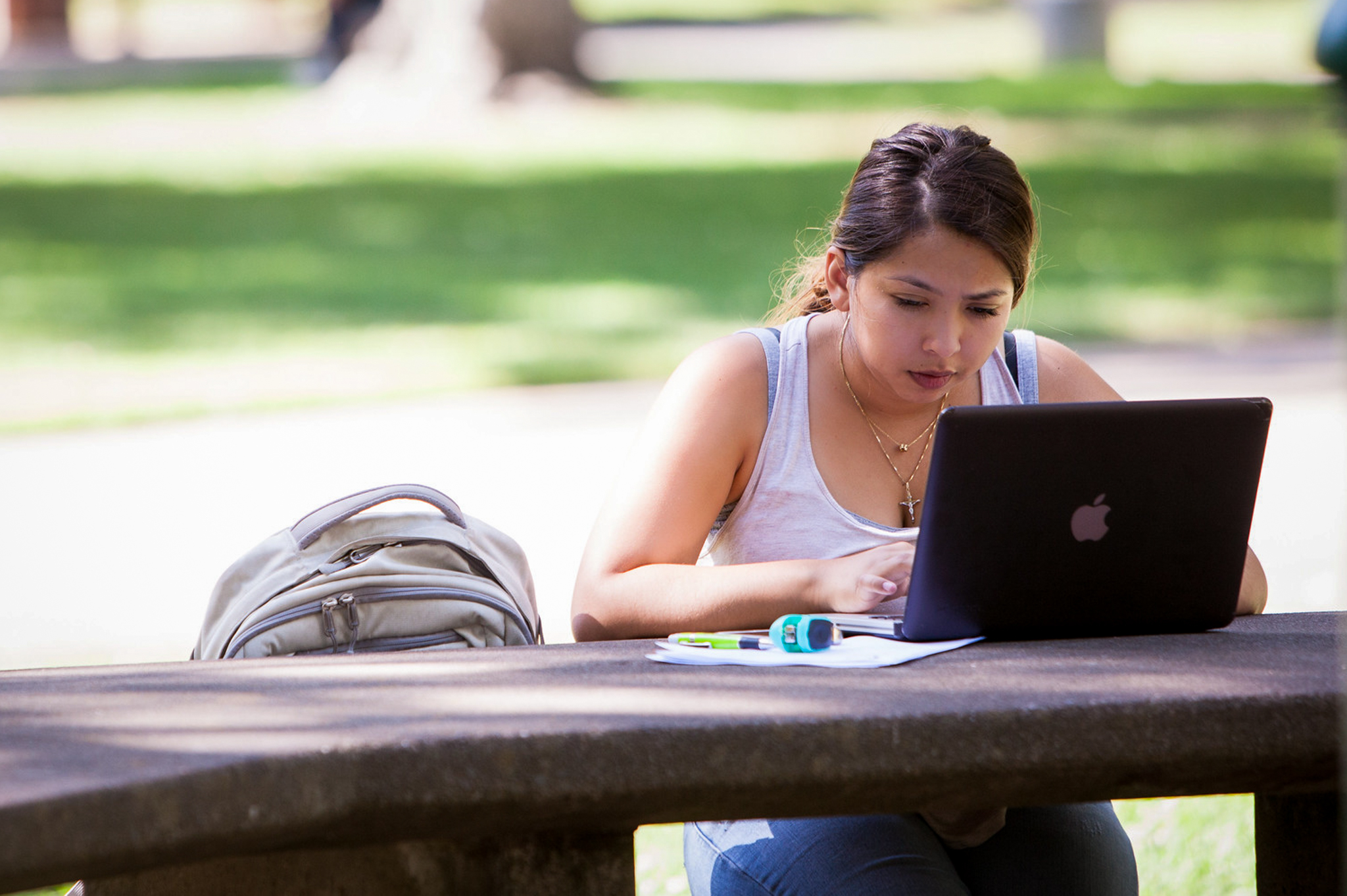 A Sacramento State student works outside on a laptop