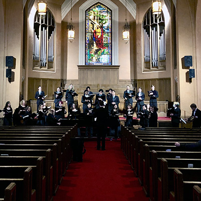 Image inside a church facing towards the altar w/singers scattered about