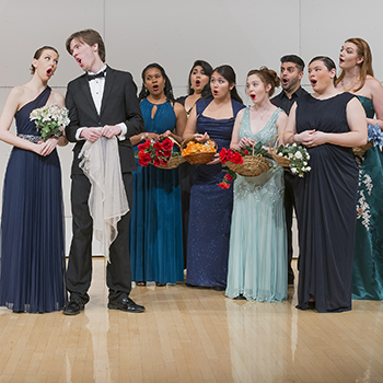 Image of opera singers in fancy dress holding flowers, singing