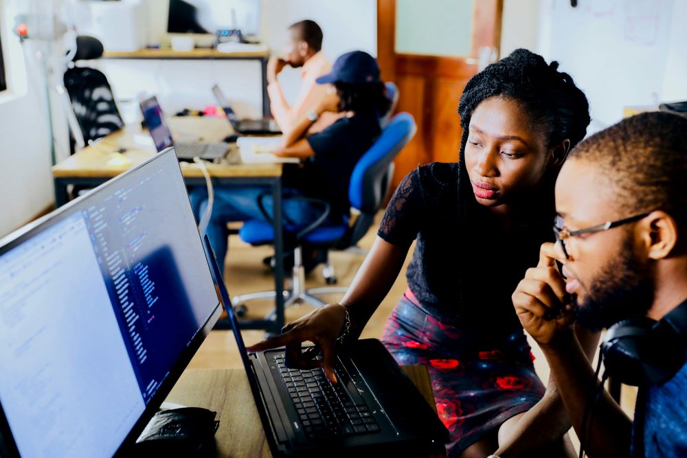 Person pointing to laptop and giving work colleague feedback