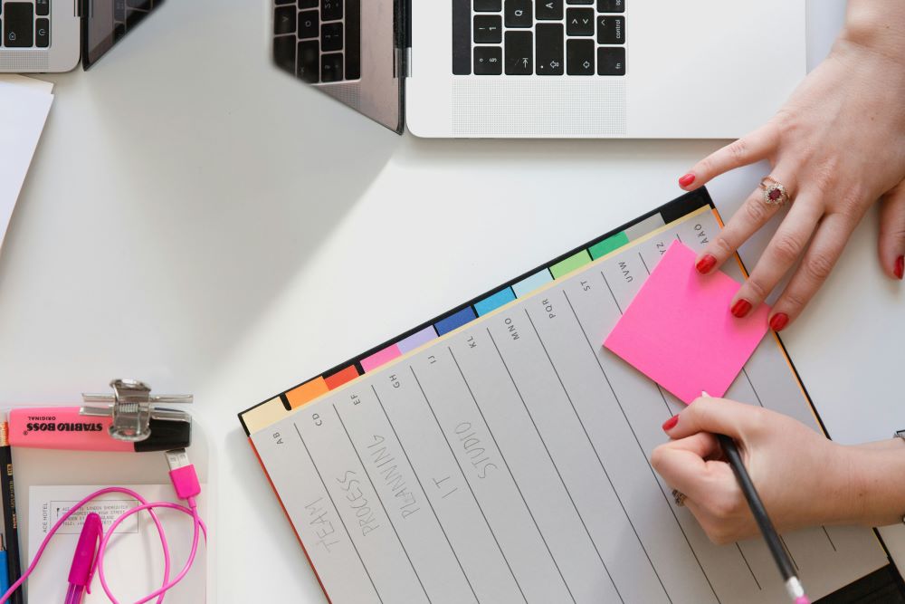 Person writing a sticky note in a planner