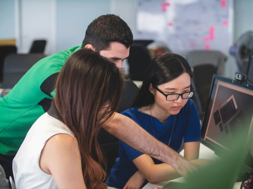 Person helping two people problem solve in an office setting