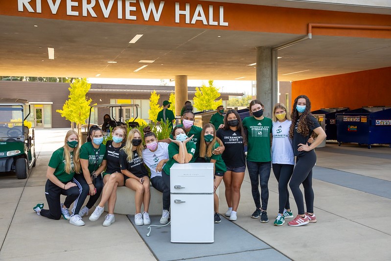 Photo of students standing around a mini fridge on move-in day