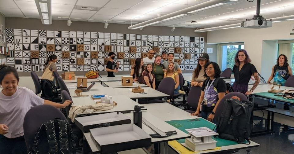 Students and faculty in a classroom with artwork on the walls