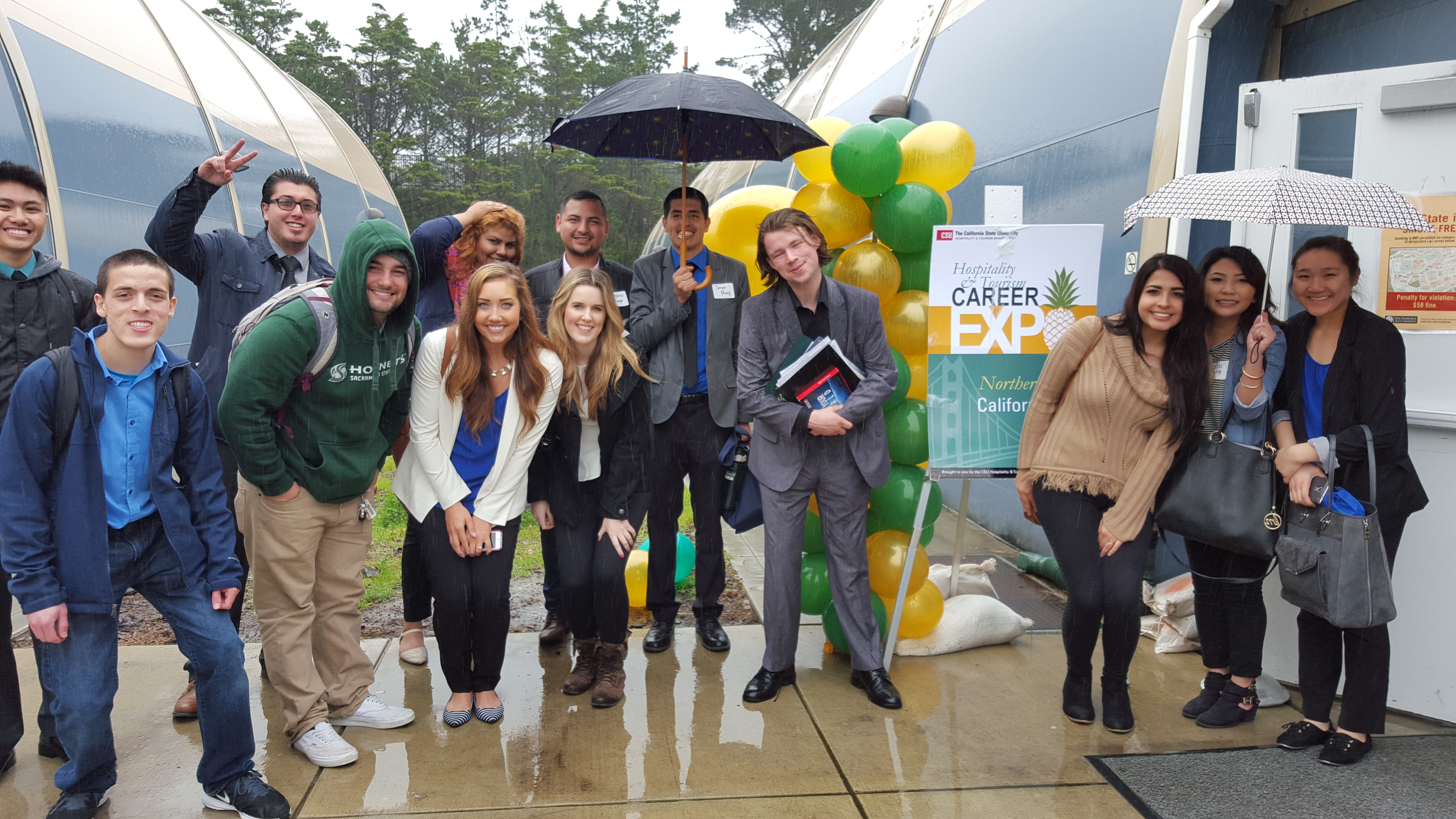 Smiling group of HTM students at a rainy career expo