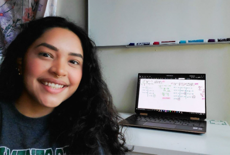 An image of a girl smiling beside her laptop