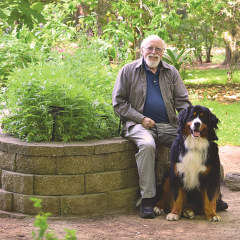 Man and dog sitting in the Sac State Arboretum