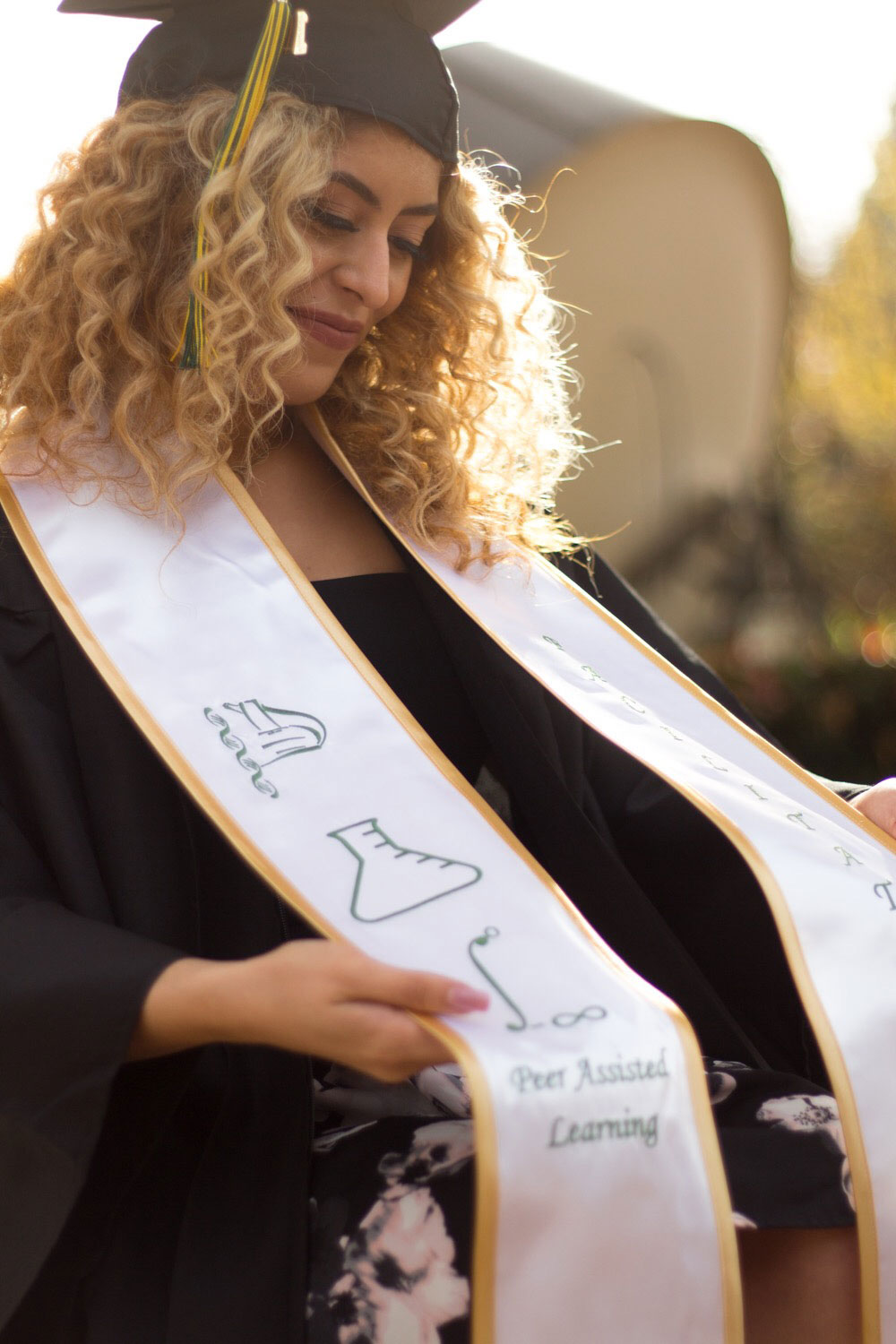 Graduate beams looking at her commencement hood