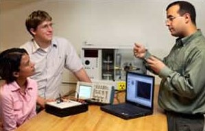 Professor discussing oscilloscopes with two students