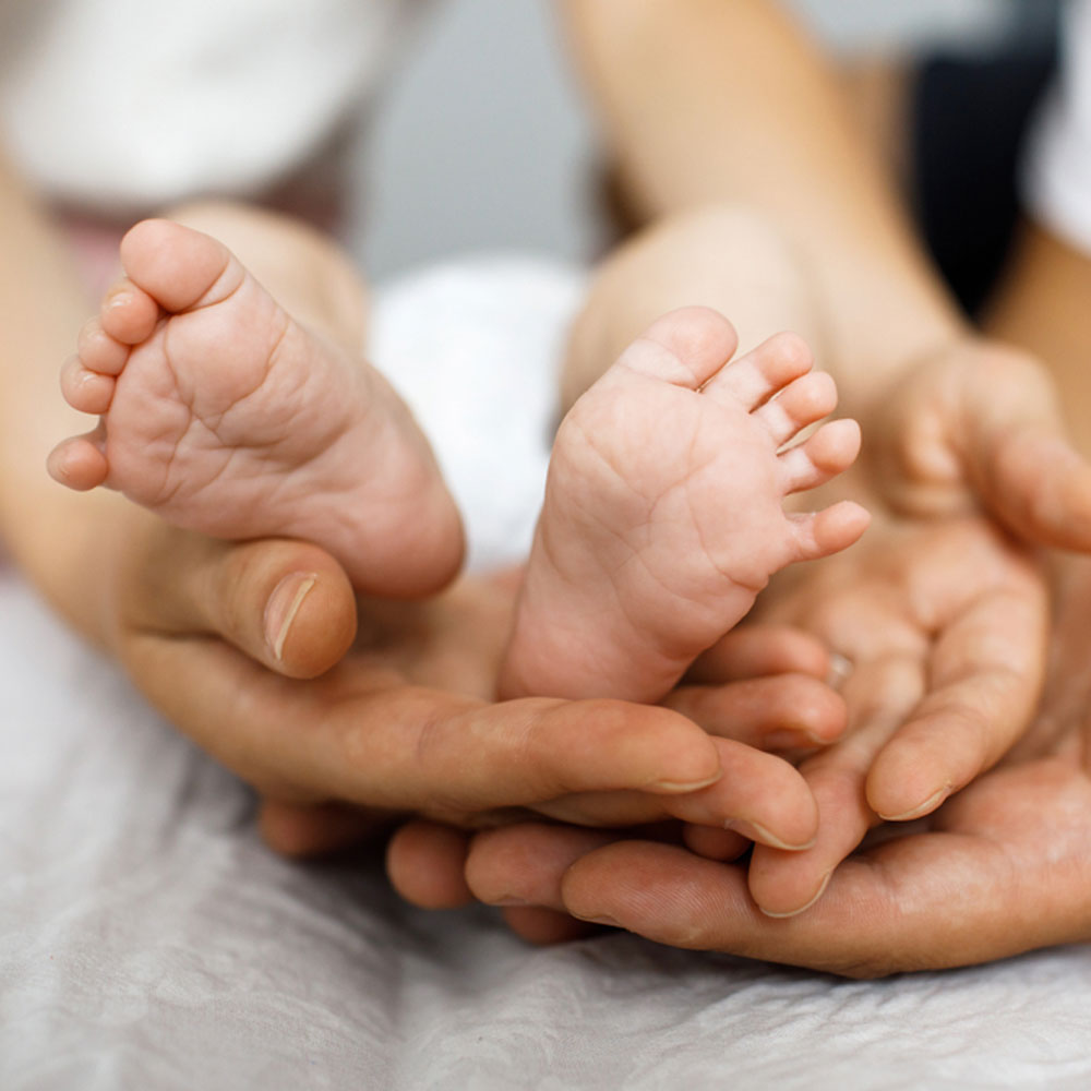 Two hands open with an infant's two feet in between the hands