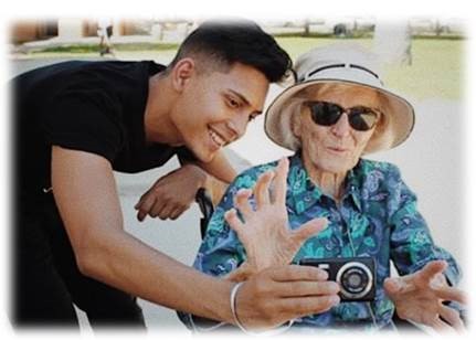 Student, Erick Camarena, showing a camera to a disabled older adult.