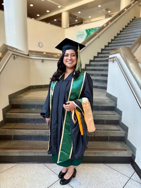 Women with cap and gown standing in front of stairs