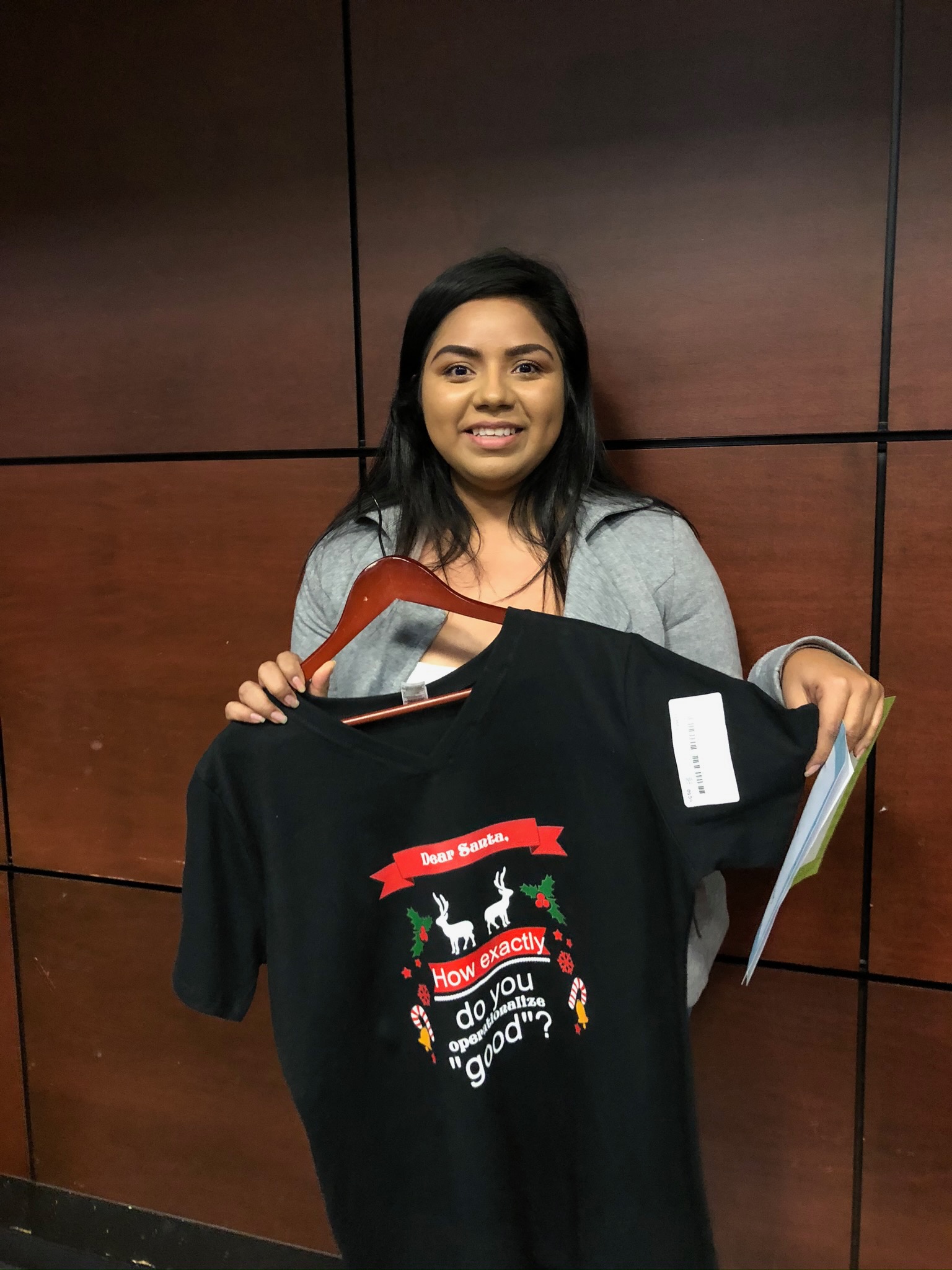 A student holding a black t-shirt that they won in a raffle.