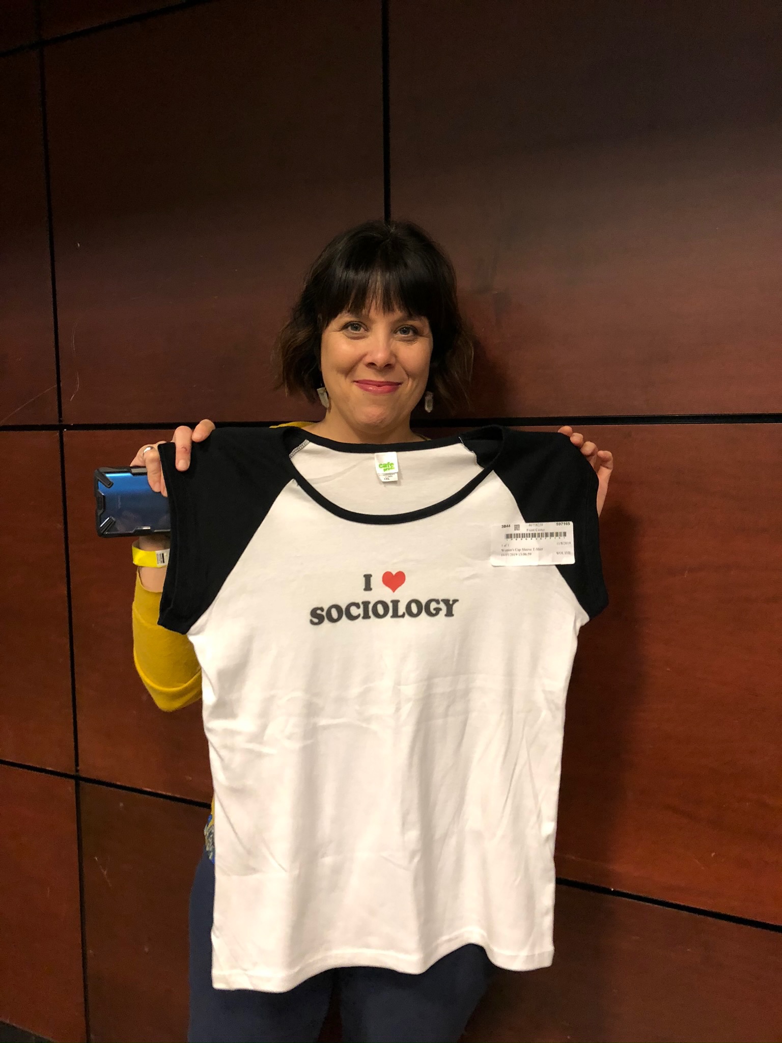  student holding a white and black t-shirt that they won in a raffle.