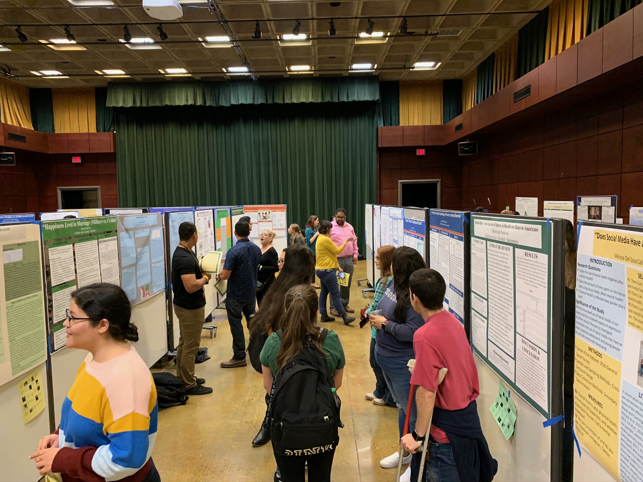 A group of 12 students talking among themselves in front of their presentations.