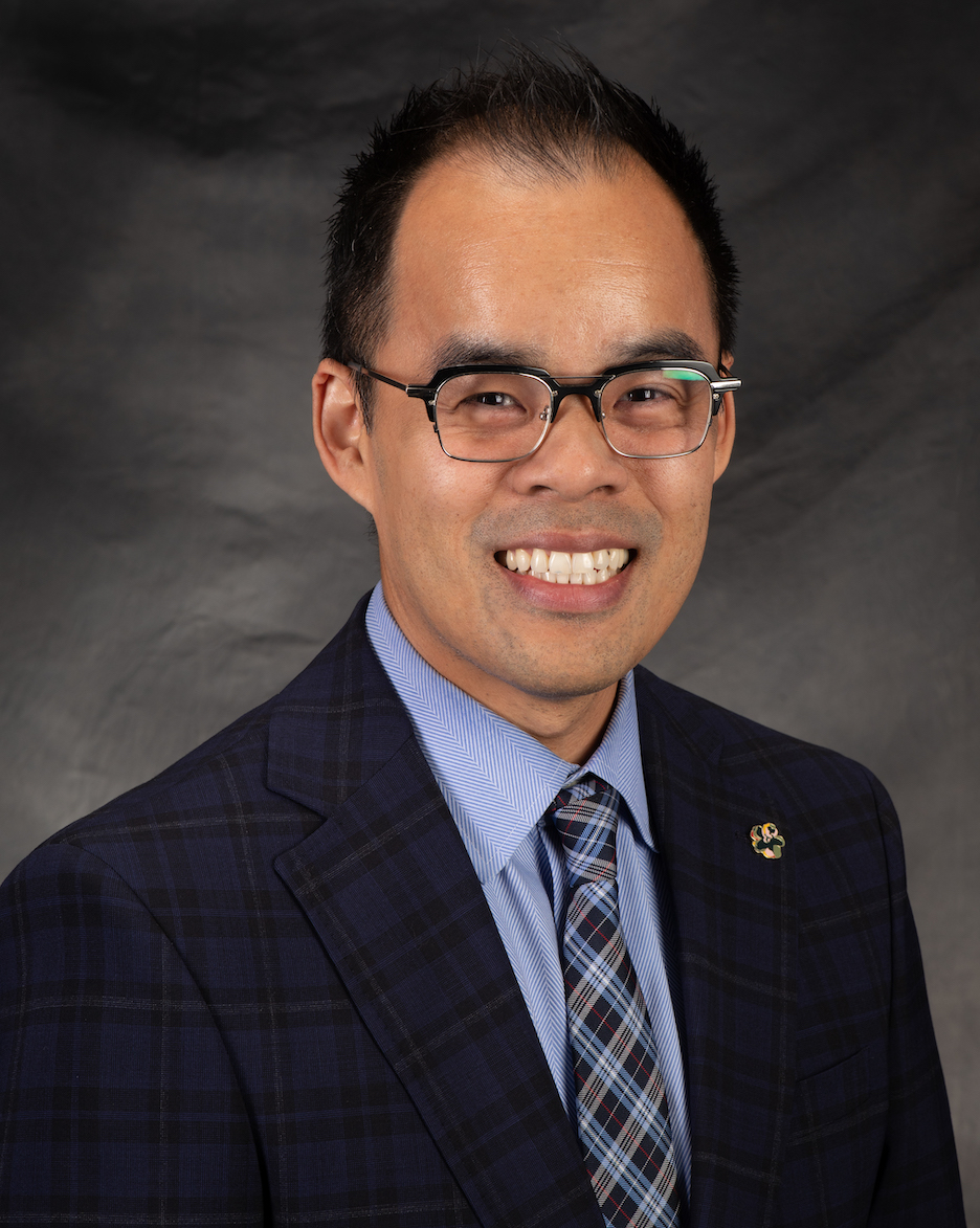 Assoiate Vice President Dr. Michael Vinh Nguyen in a blue plaid suit with a light blue herringbone striped shirt, and a blue plaid tie.