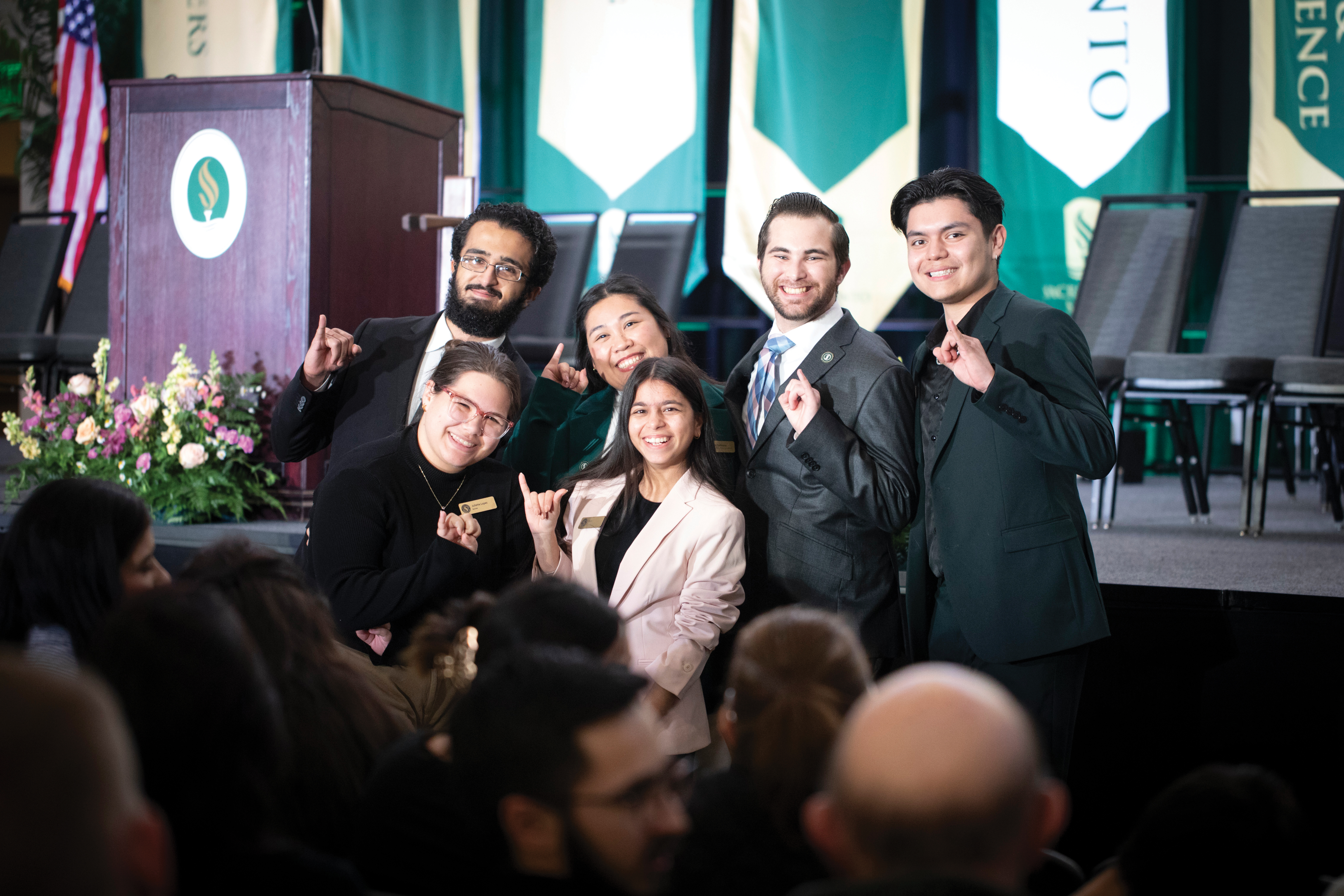 Image: male and female students smiling and doing stingers up