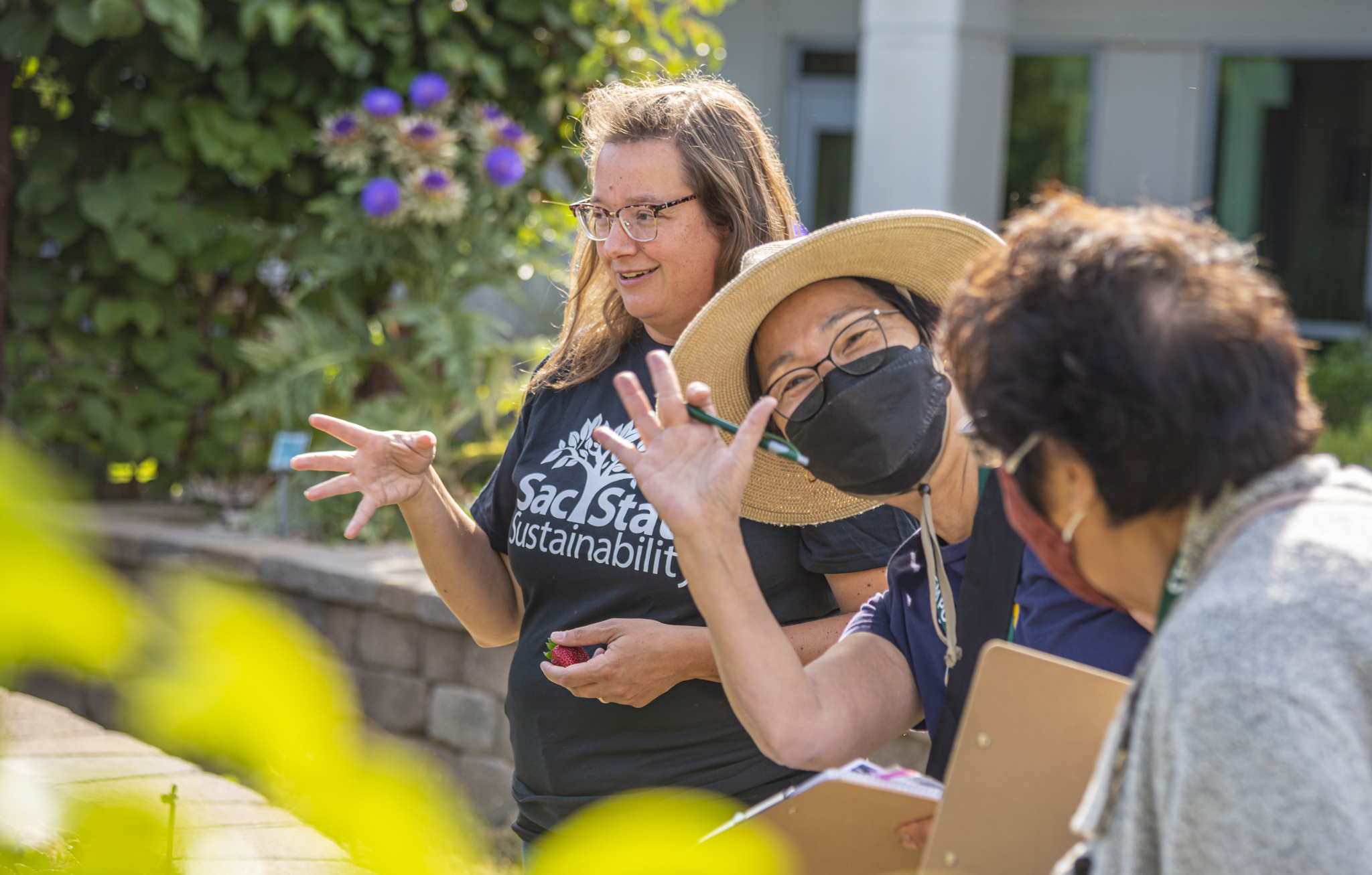 Teacher waves to camera at garden