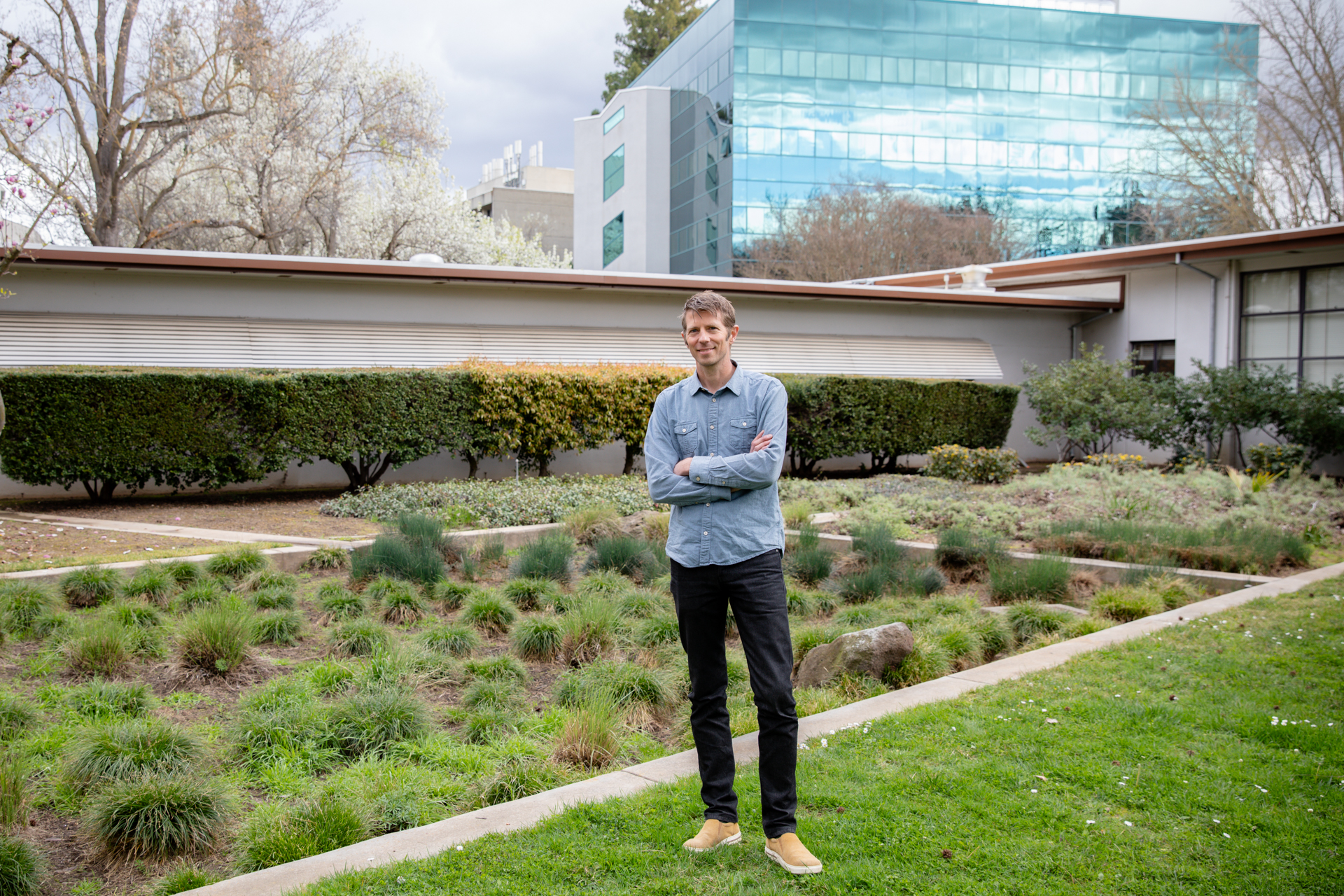 professor standing on grass in front of a building