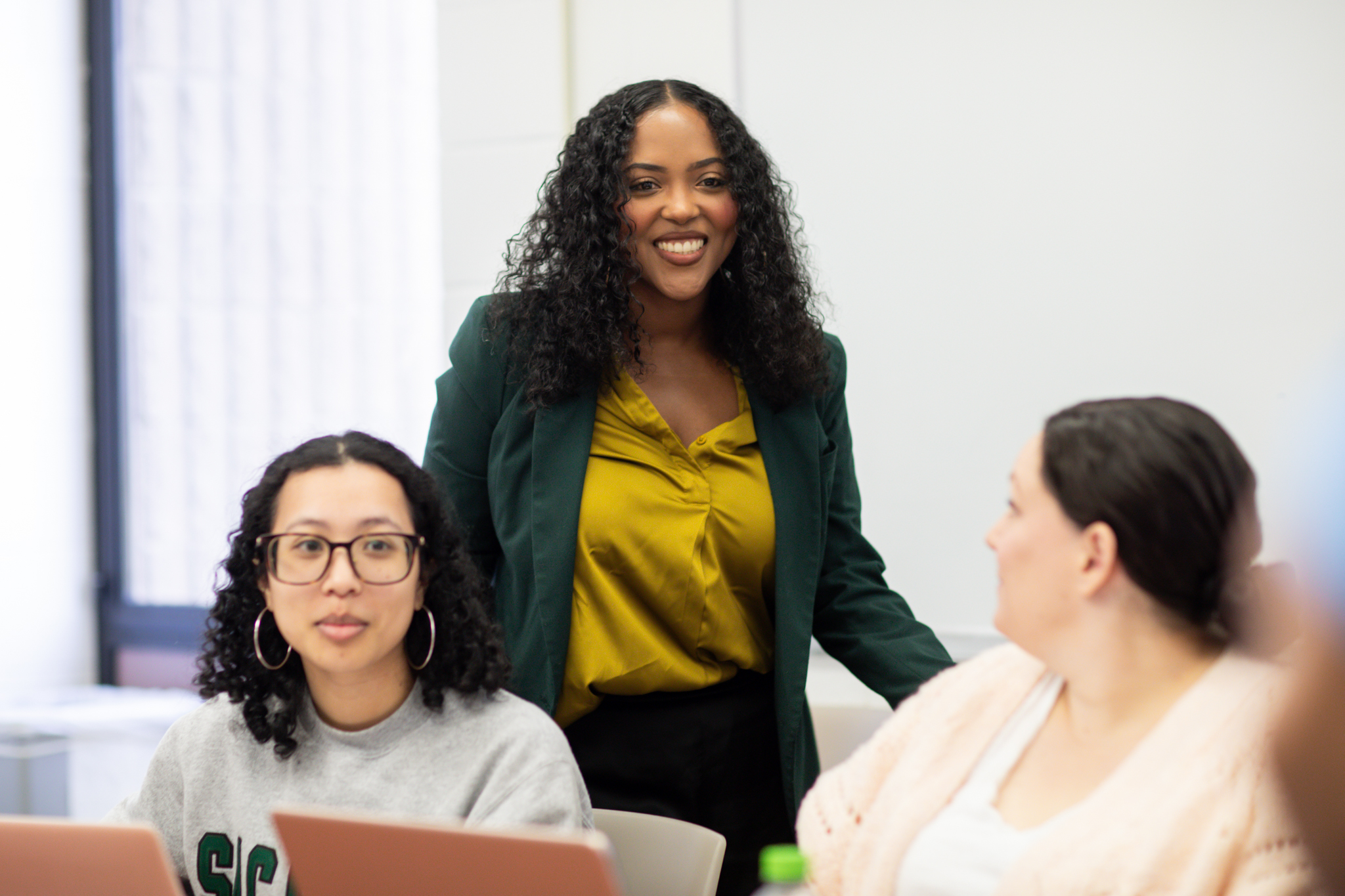 Brittany Young, standing in a classroom behind two students.