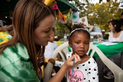 A child getting a flower painted on her cheek