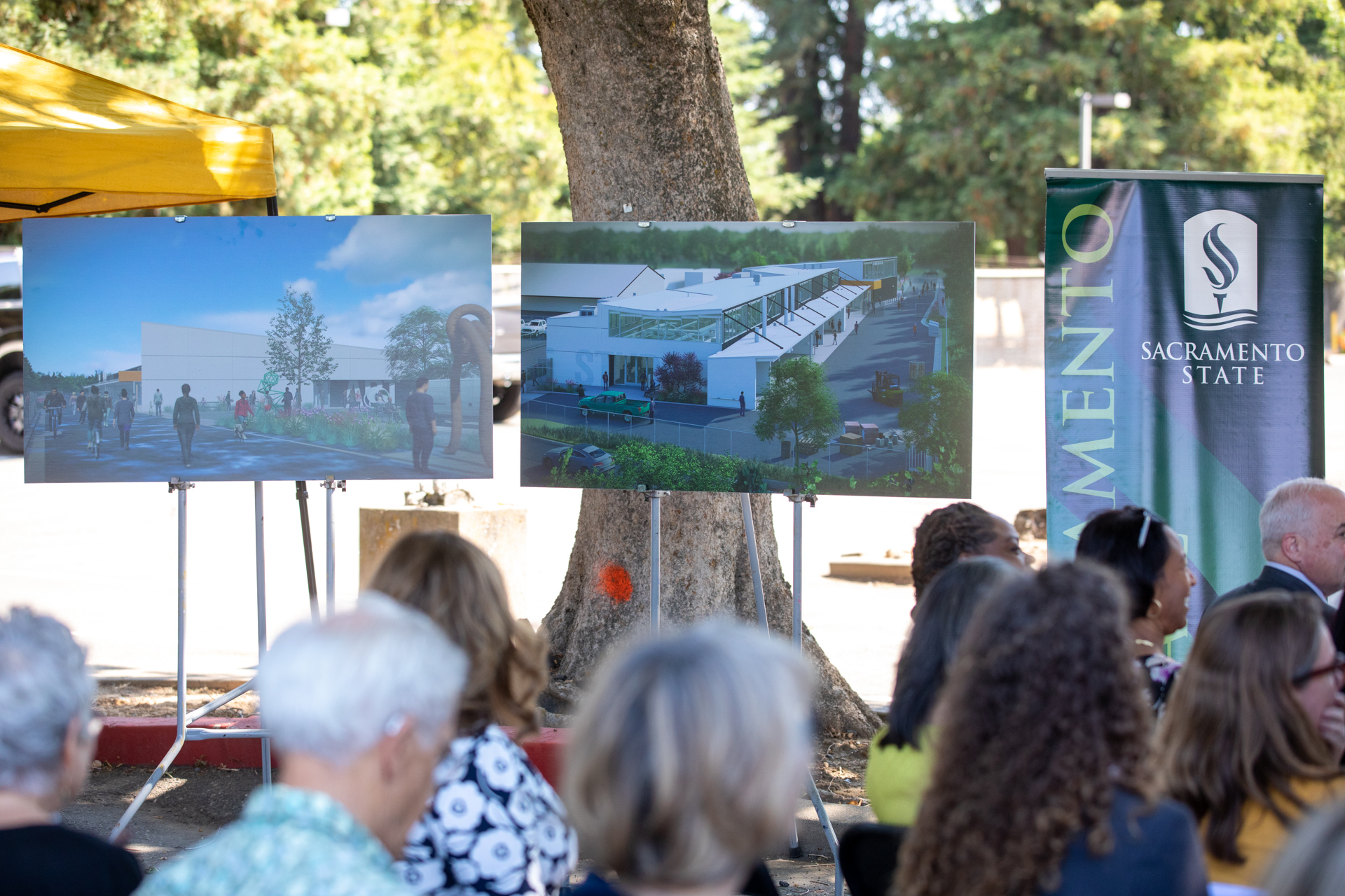 Attendees at the groundbreaking with renderings of the new building