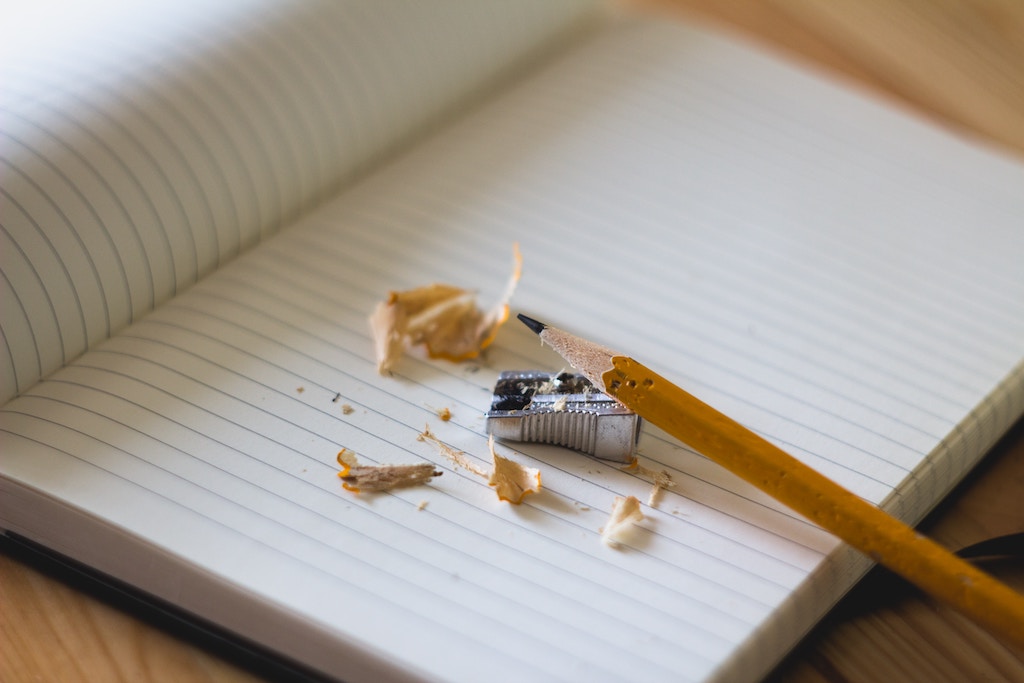 Decorative photo of a blank notebook and a sharpened pencil