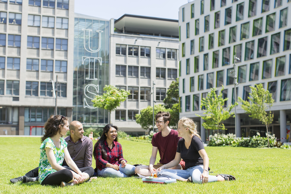 Group of students sitting on the law in front of the dorms.