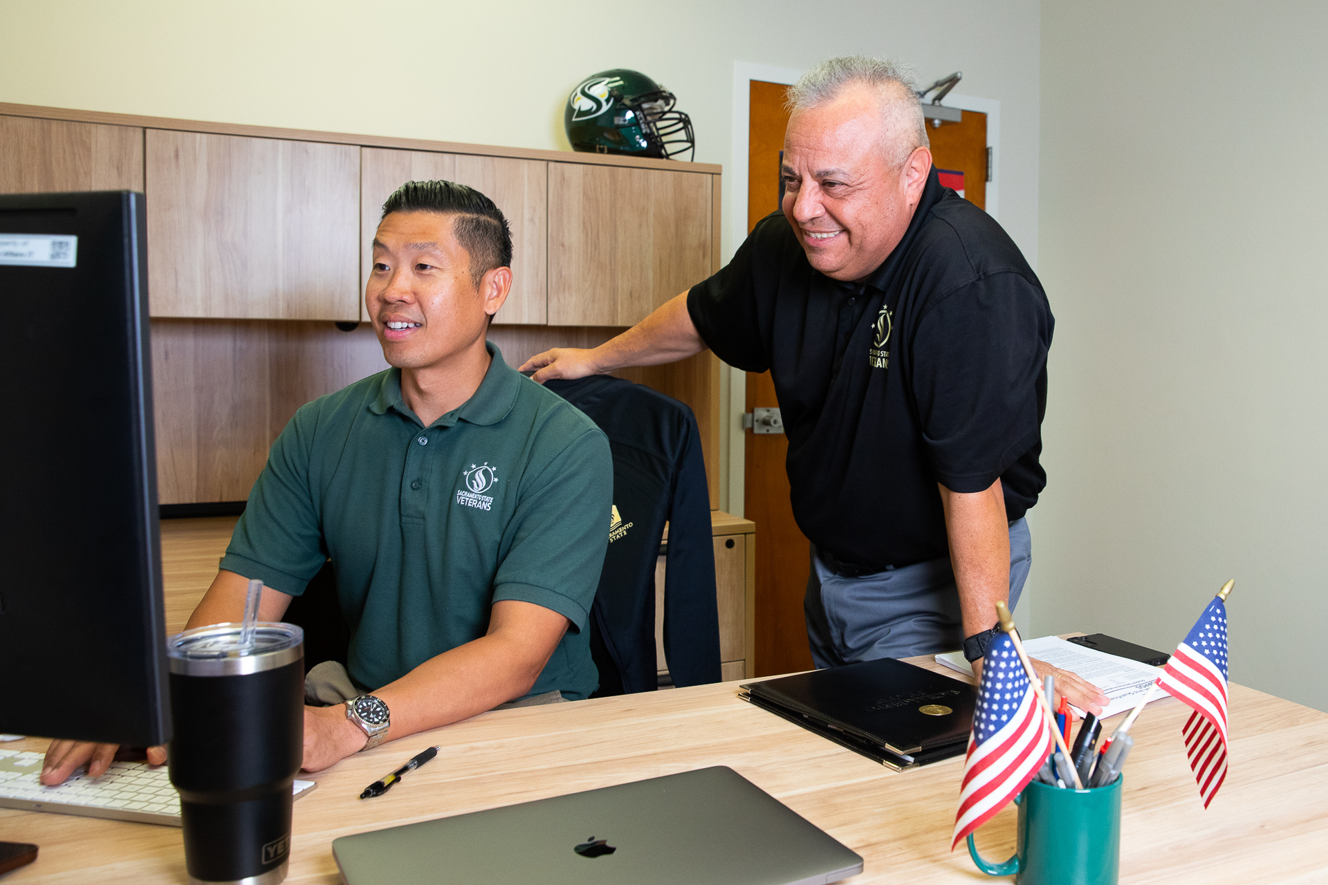 Austin Sihoe sits at a computer, with Mario Garza looking over his shoulder, in the Veterans Success Center