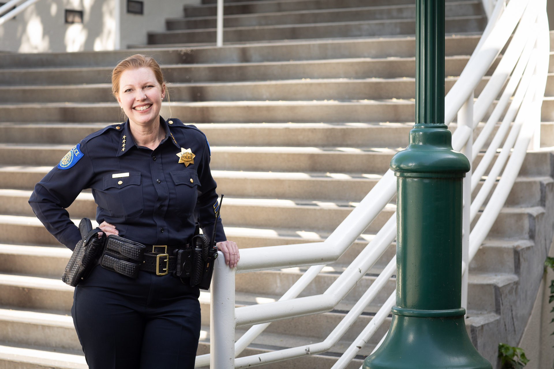 Sacramento Police Chief Kathy Lester, in uniform, standing outside in front of a staircase.