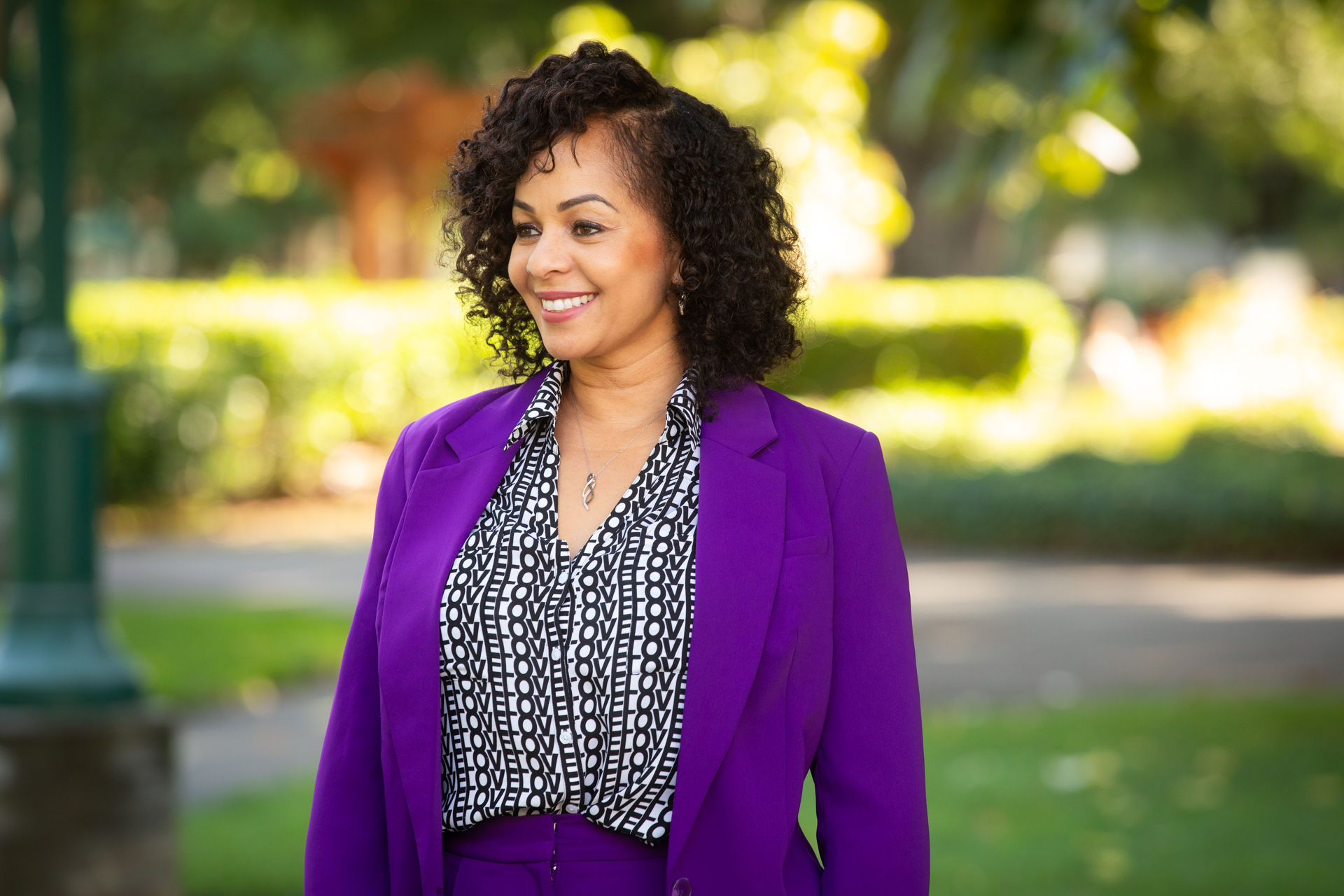 Tanya Brownrigg, wearing a purple suit in recognition of Domestic Violence Awareness Month, stands outdoors on the Sac State campus