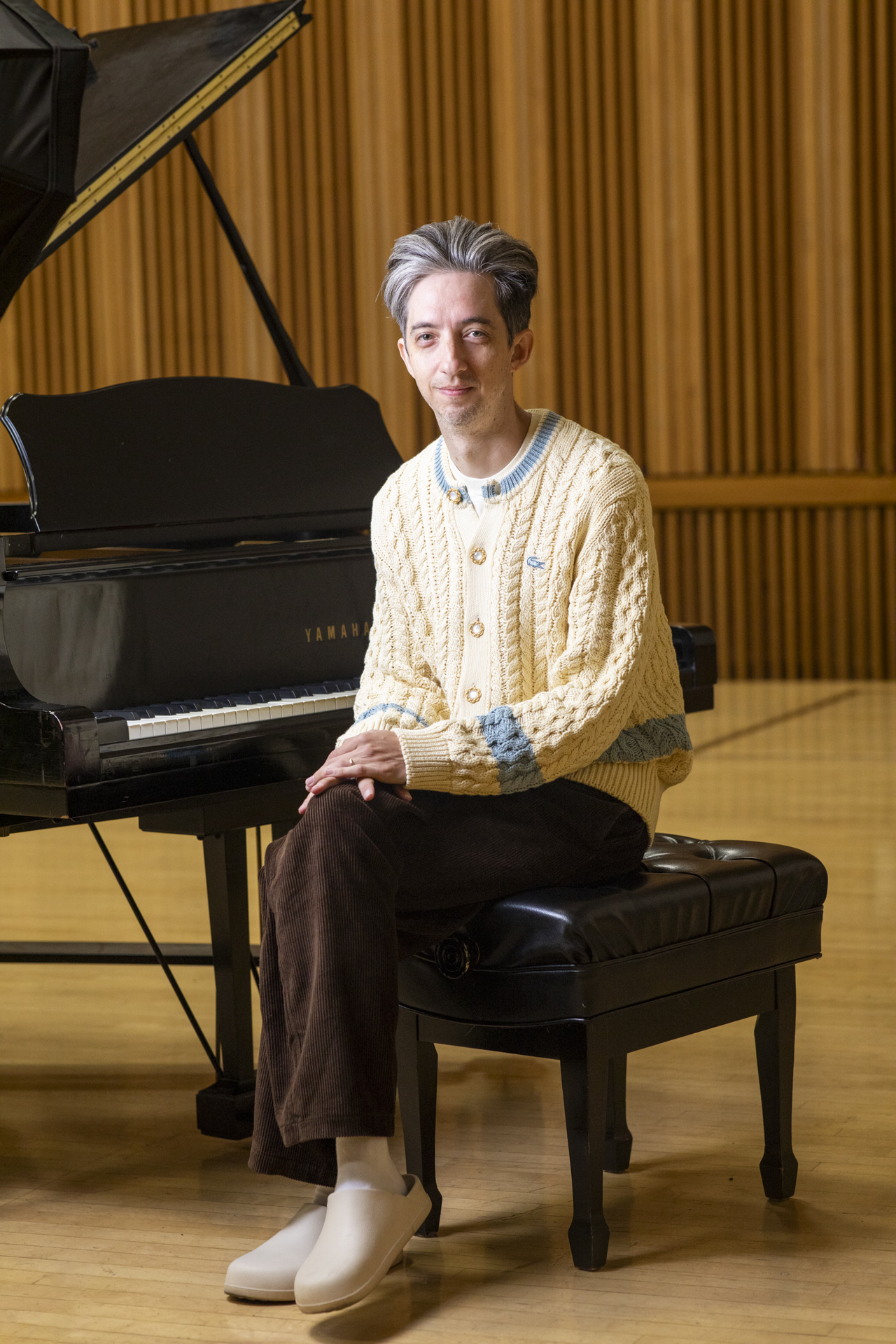 Cole Cuchna seated at a grand piano inside a recital hall.