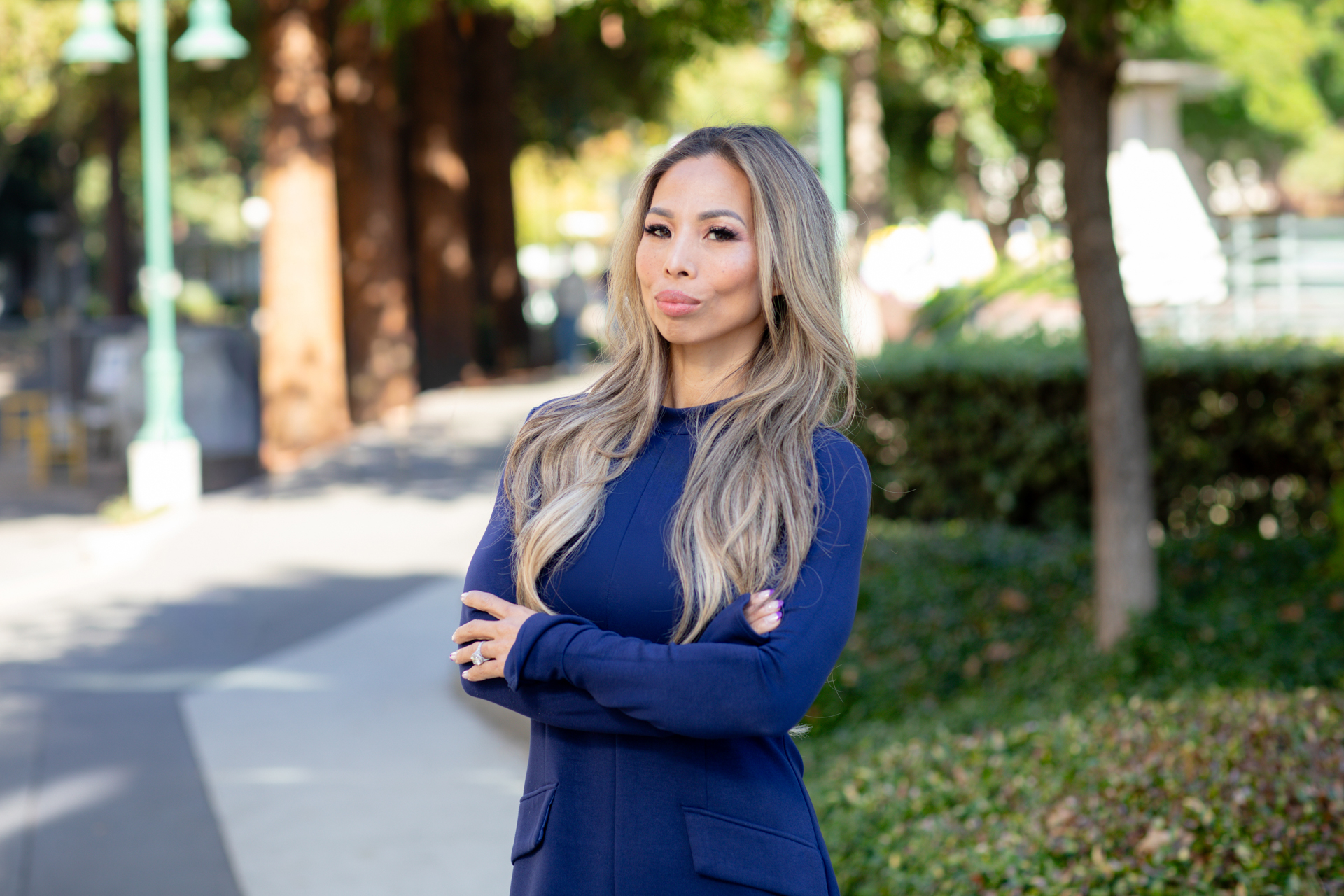 Attorney and Sac State alum Anh Phoong poses in a blue dress on campus with trees in background.