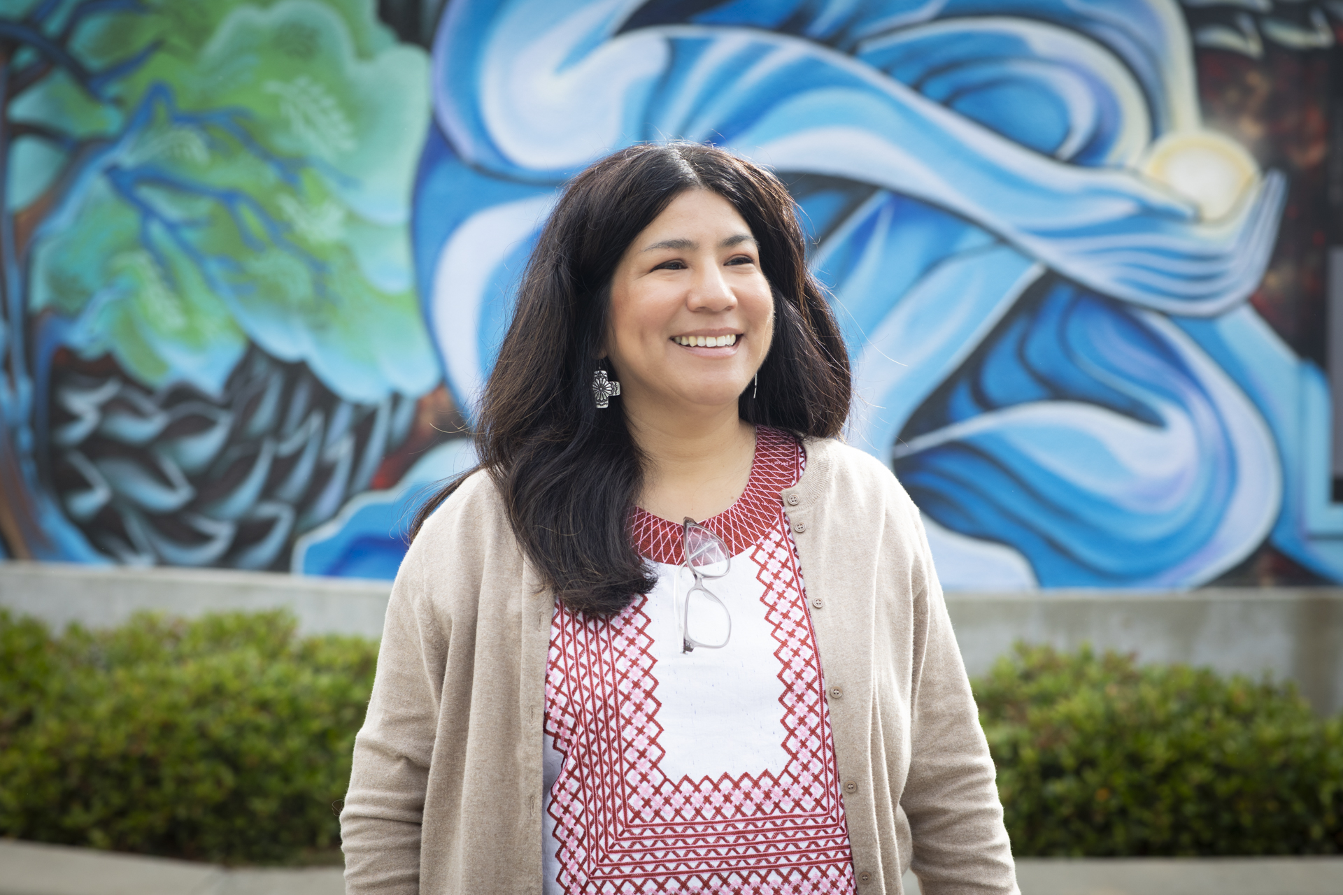 Gema Godina poses in front of a mural at Washington Elementary School. 