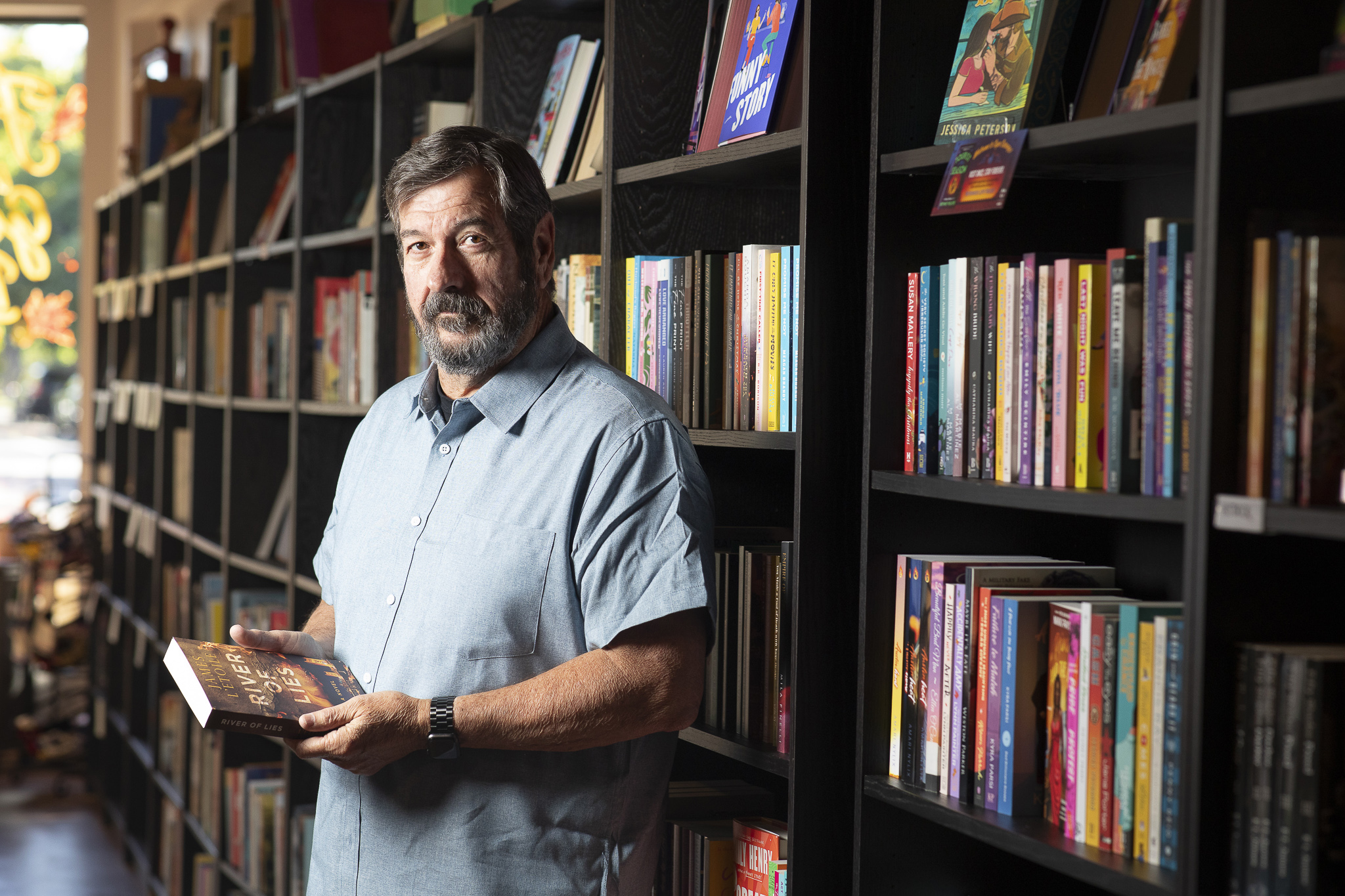 Author James L'Etoile stands in front of a bookcase full of books.