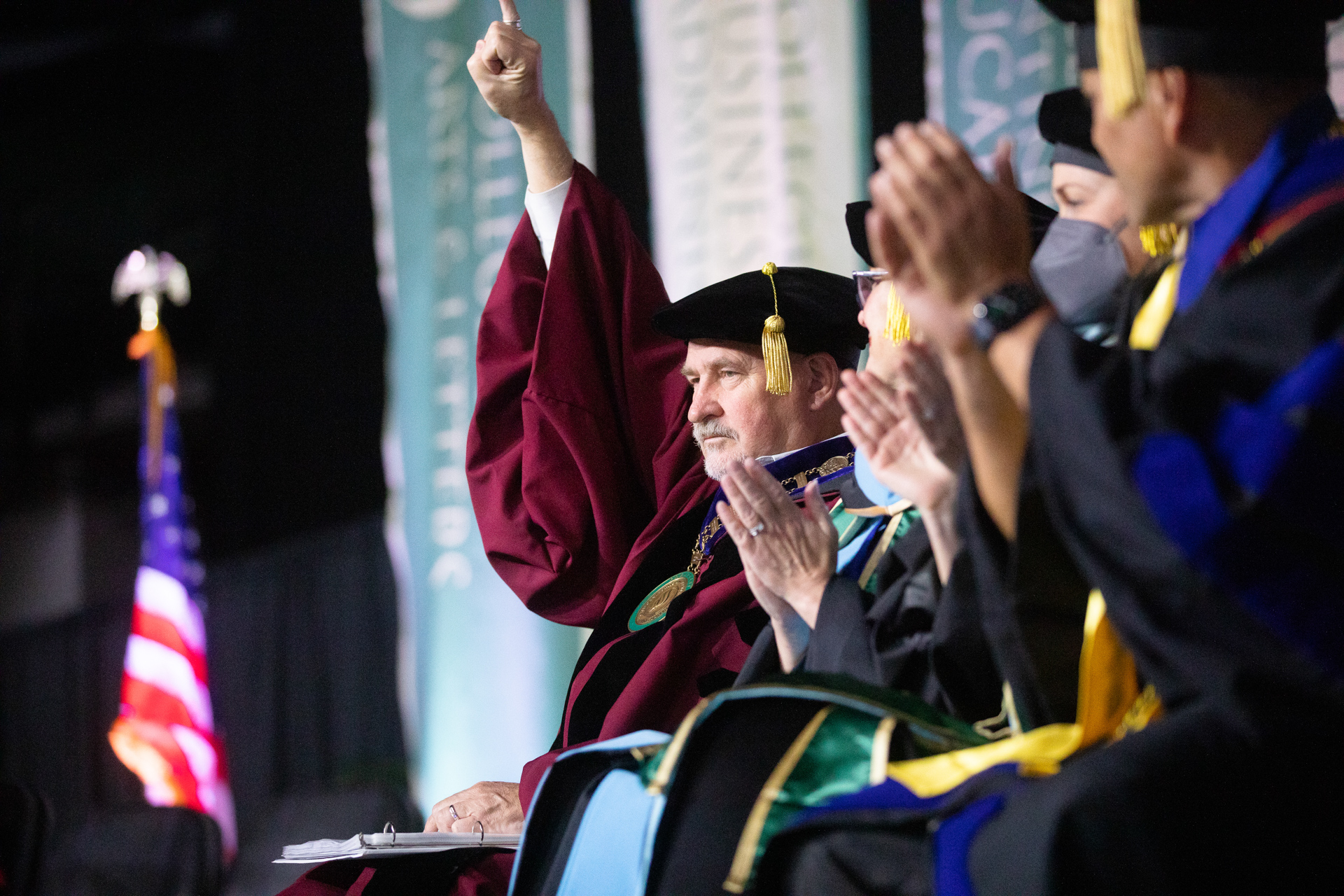 President Robert S. Nelsen, at Commencement in academic regalia, giving the "stingers up" hand signal.