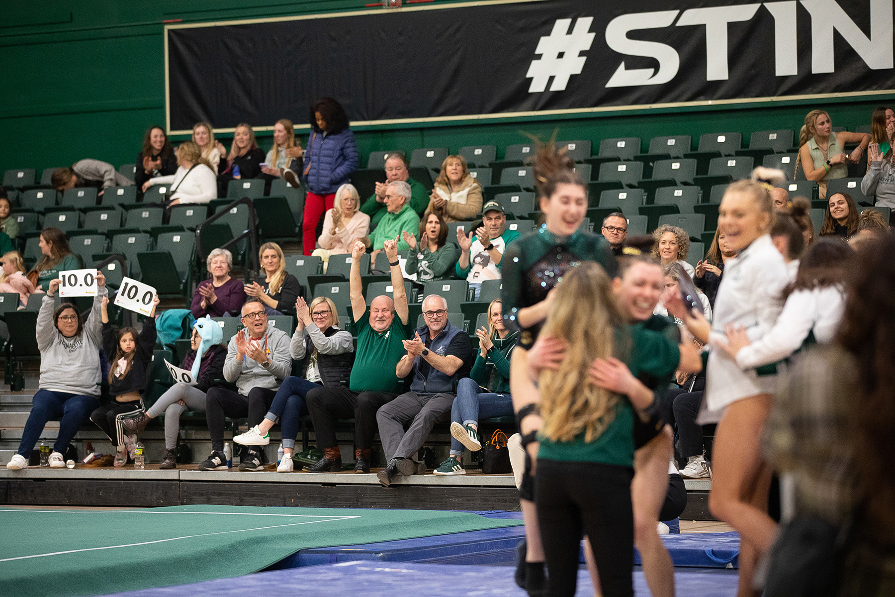 A crowd including President Robert S. Nelsen watches a Sacramento State gymnastics competition.
