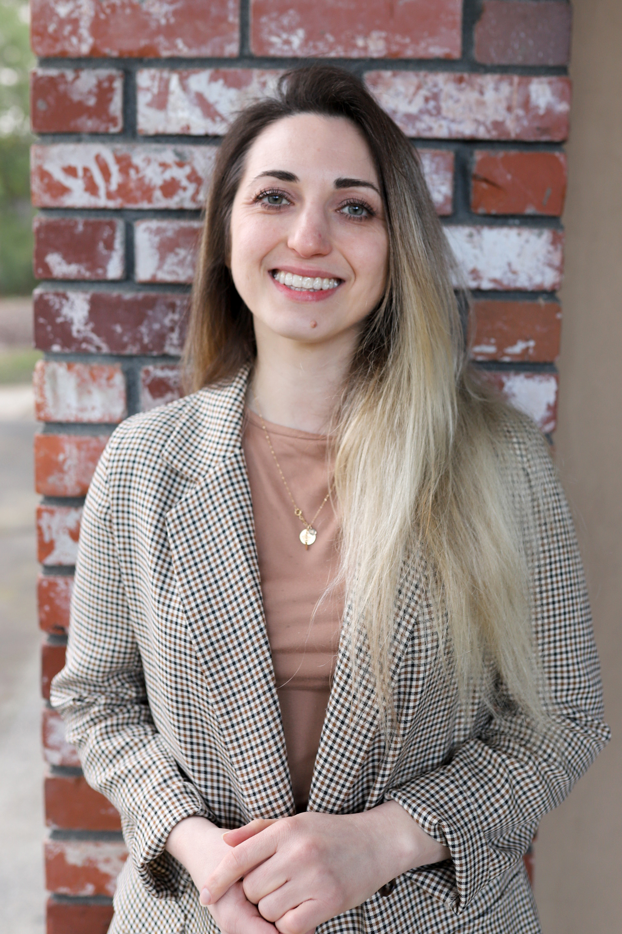 Vira Sypyuk poses on a red brick background.