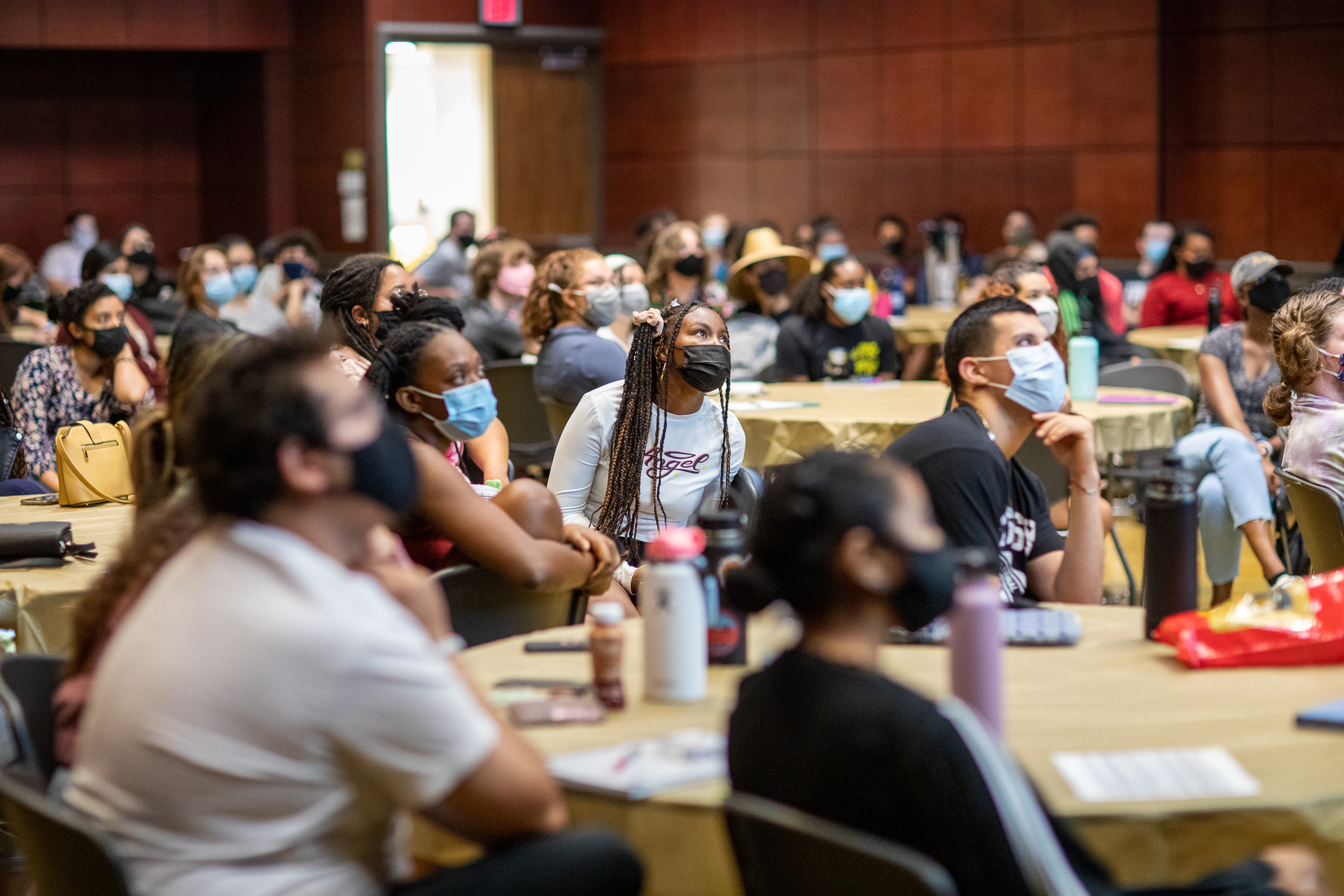 Students sitting at a table during bystander intervention training, listening to a speaker