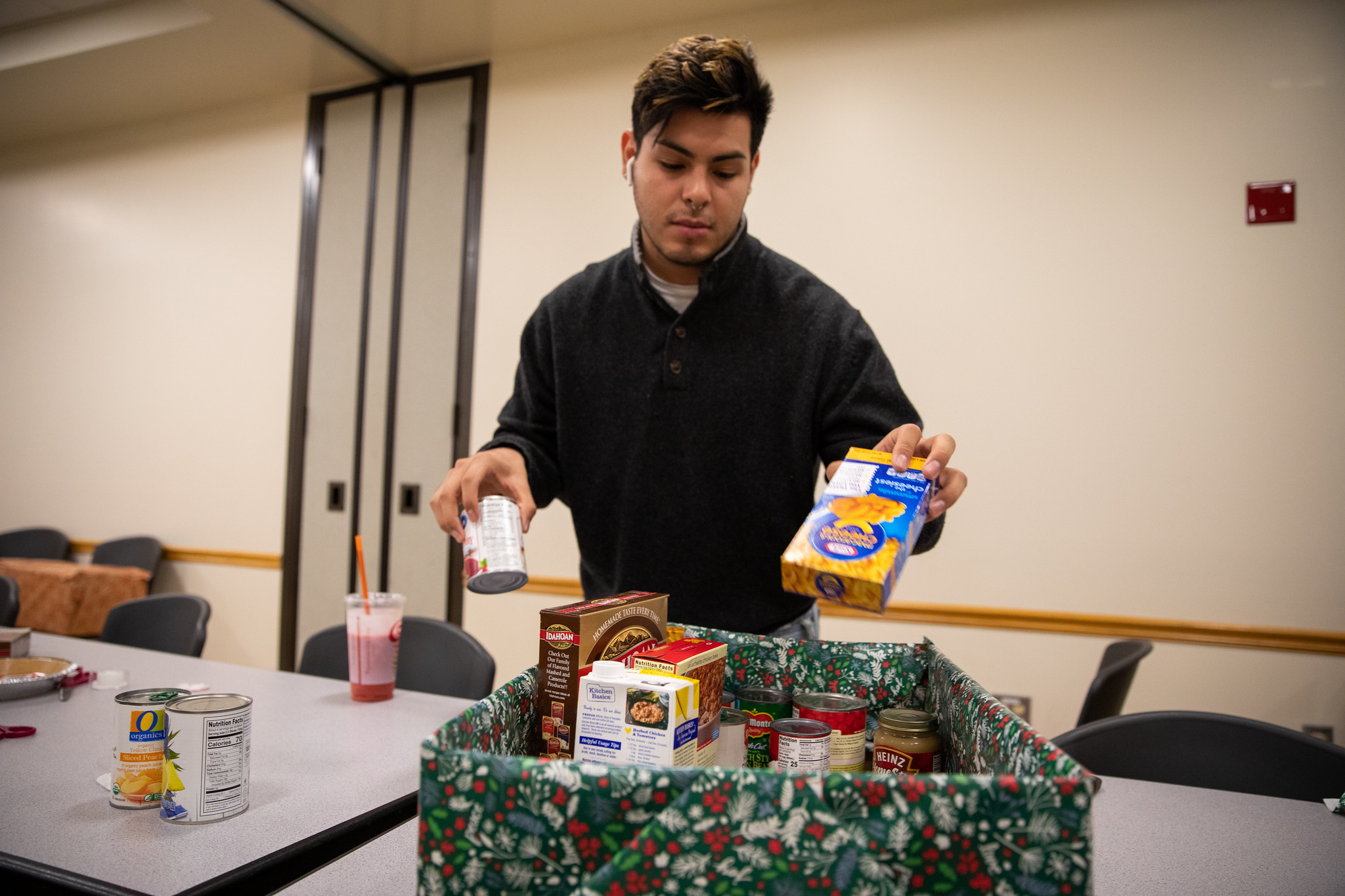 An ASI volunteer packs macaroni and cheese and canned goods into a Thanksgiving food basket.