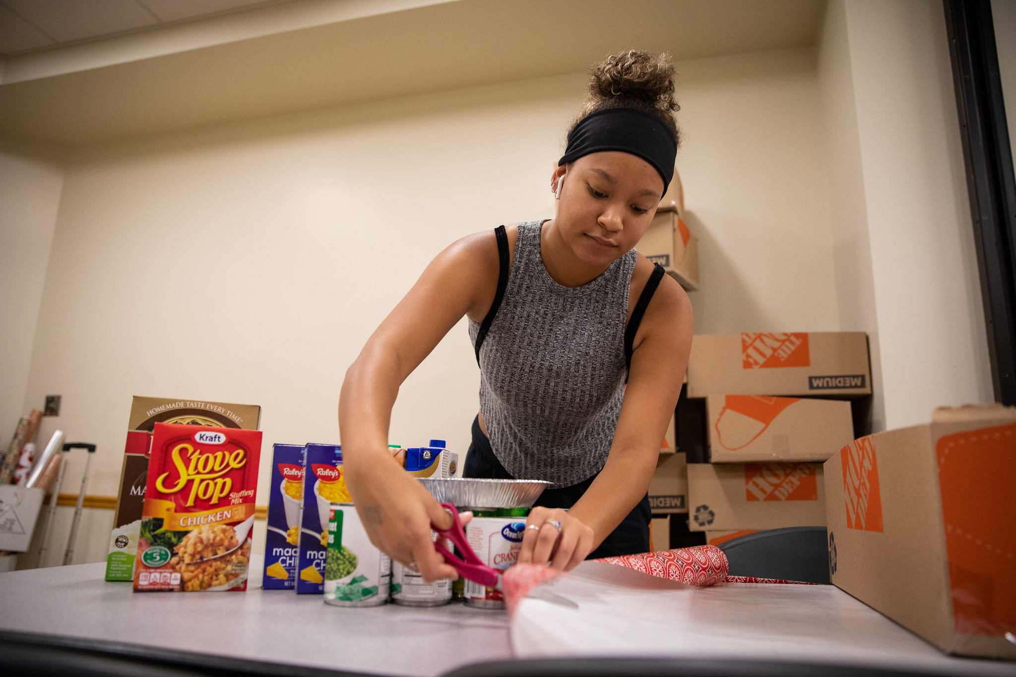 An ASI volunteer prepares a box that will be used as a Thanksgiving food basket.