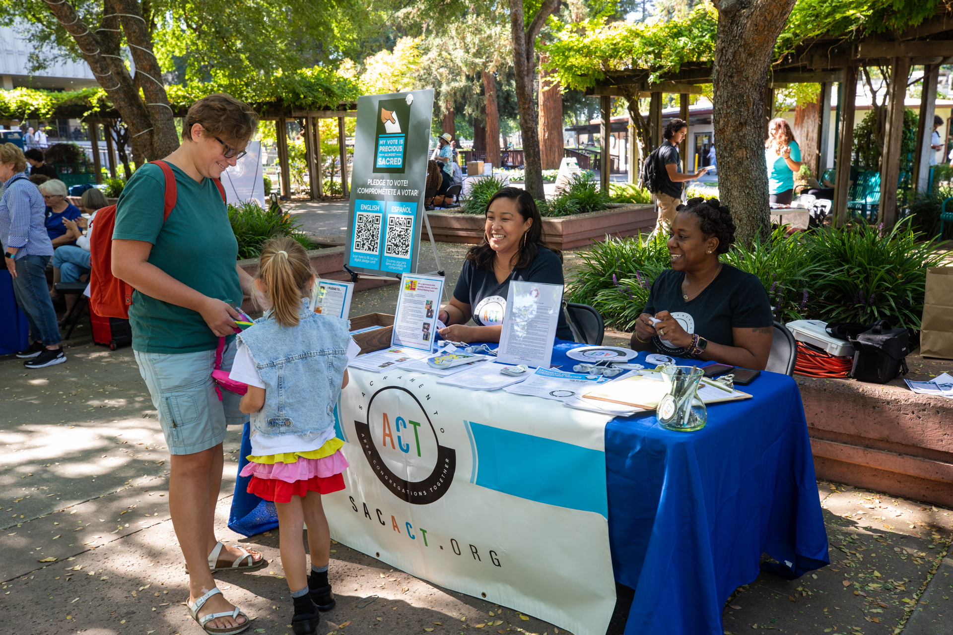 A woman and child visit the Sacramento ACT table at the Civic Engagement Resource Fair in the Library Quad at Sac State. 