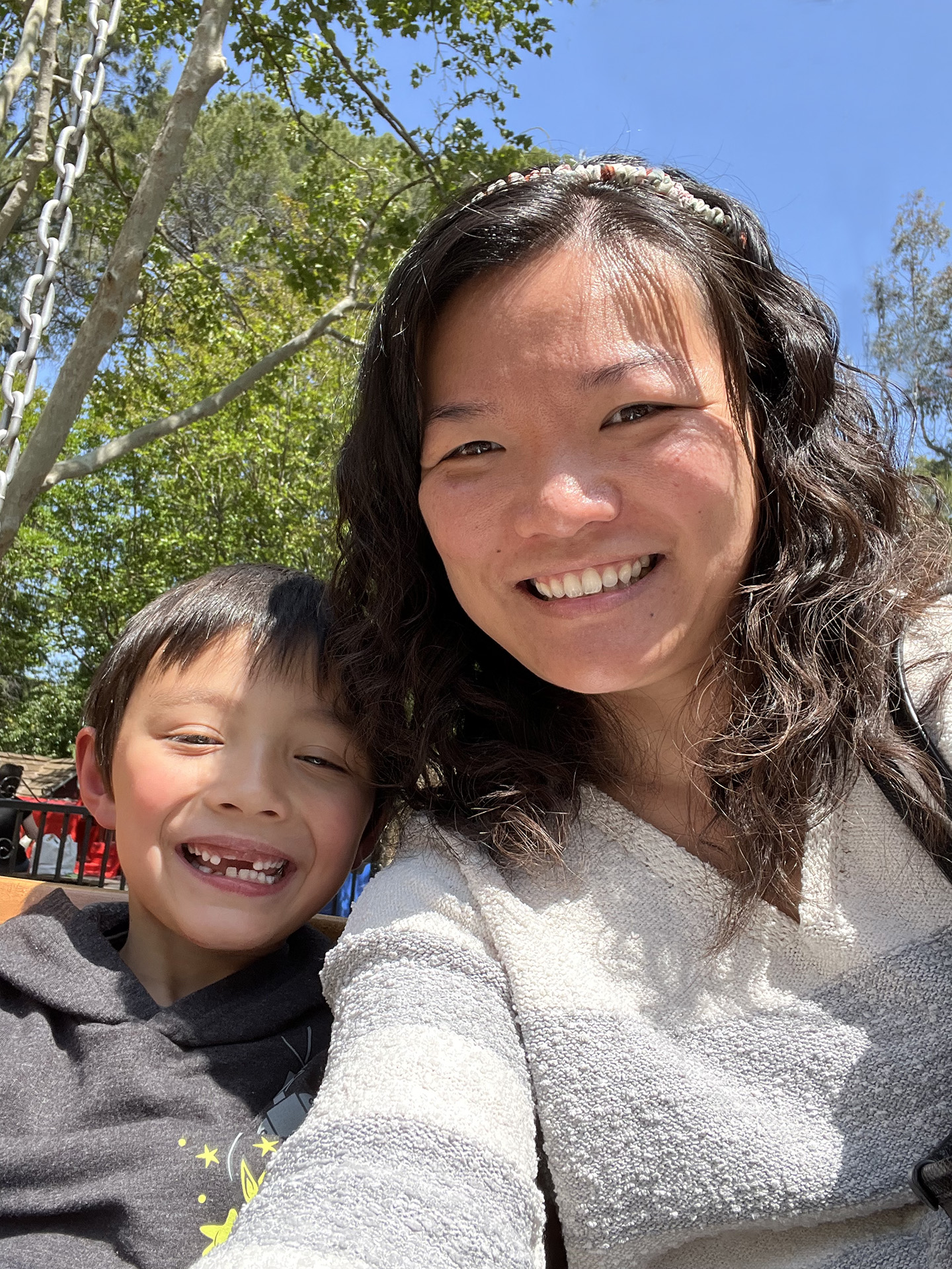 Sac State graduate Mikaela Huang and son Edoardo smile against the backdrop of a playground.
