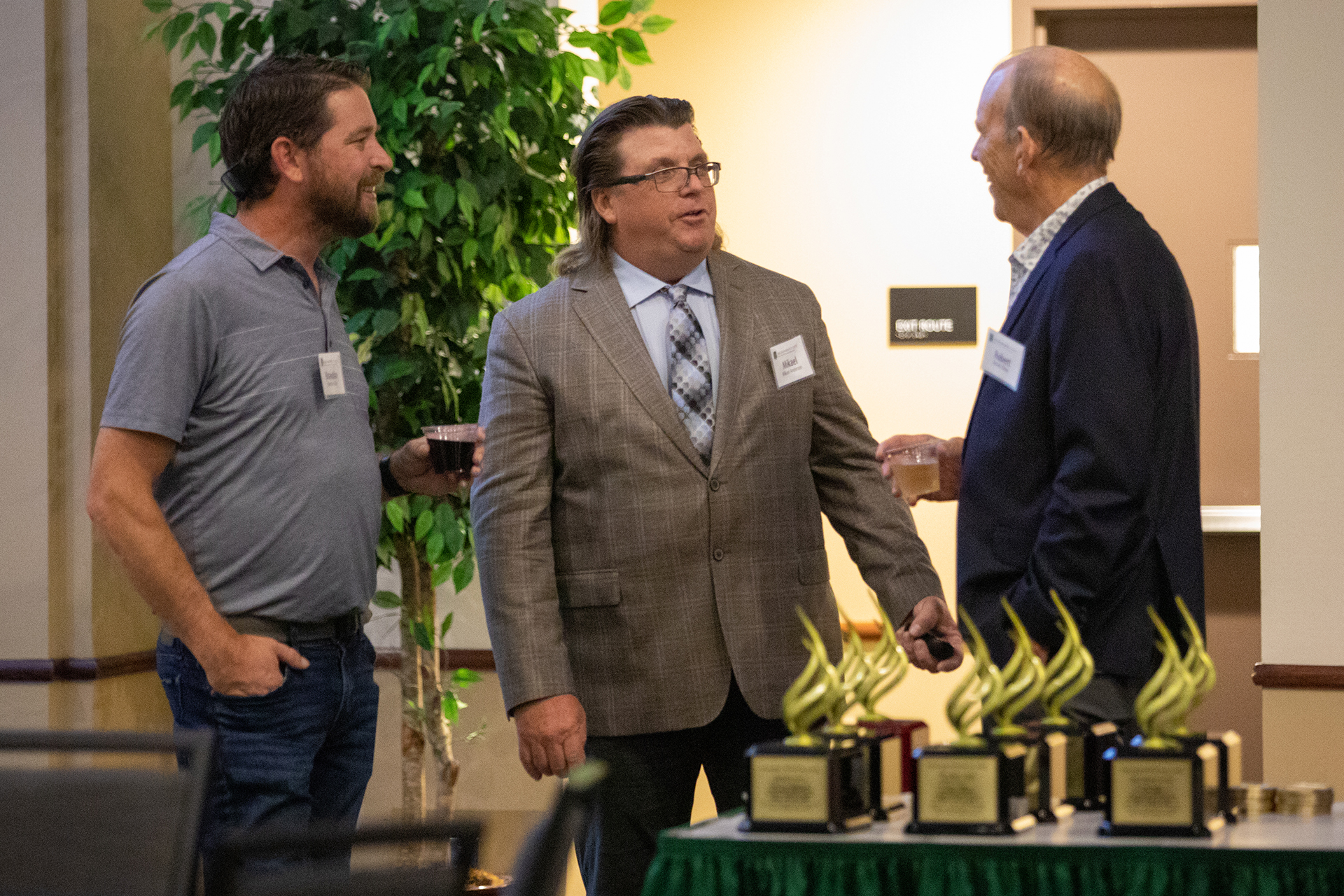Sacramento State's Construction Management Department Chair Mikael Anderson and two members of the CM family chat near a table full of awards during the program's 50th anniversary event.