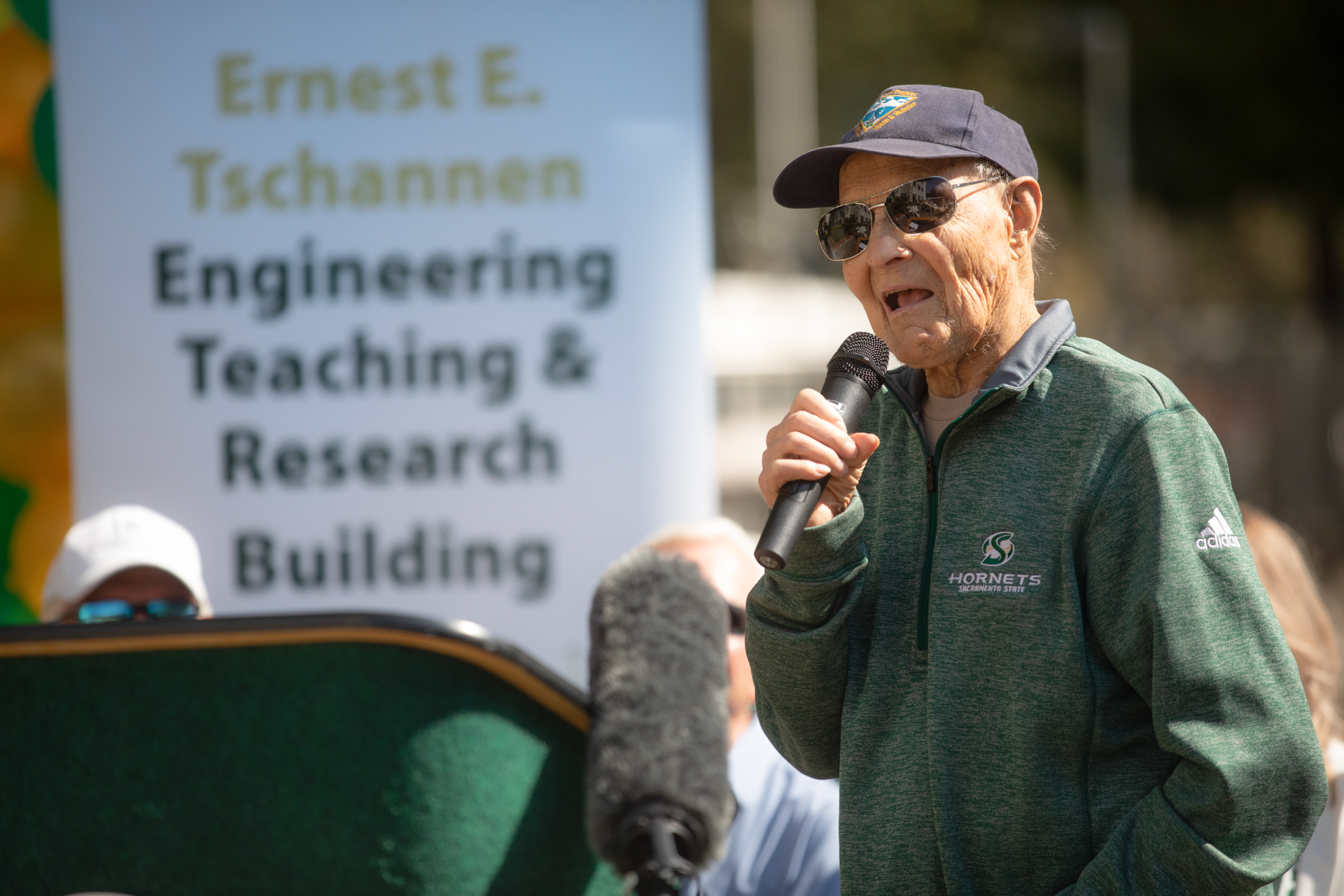 Ernest E. Tschannen holding a microphone and speaking