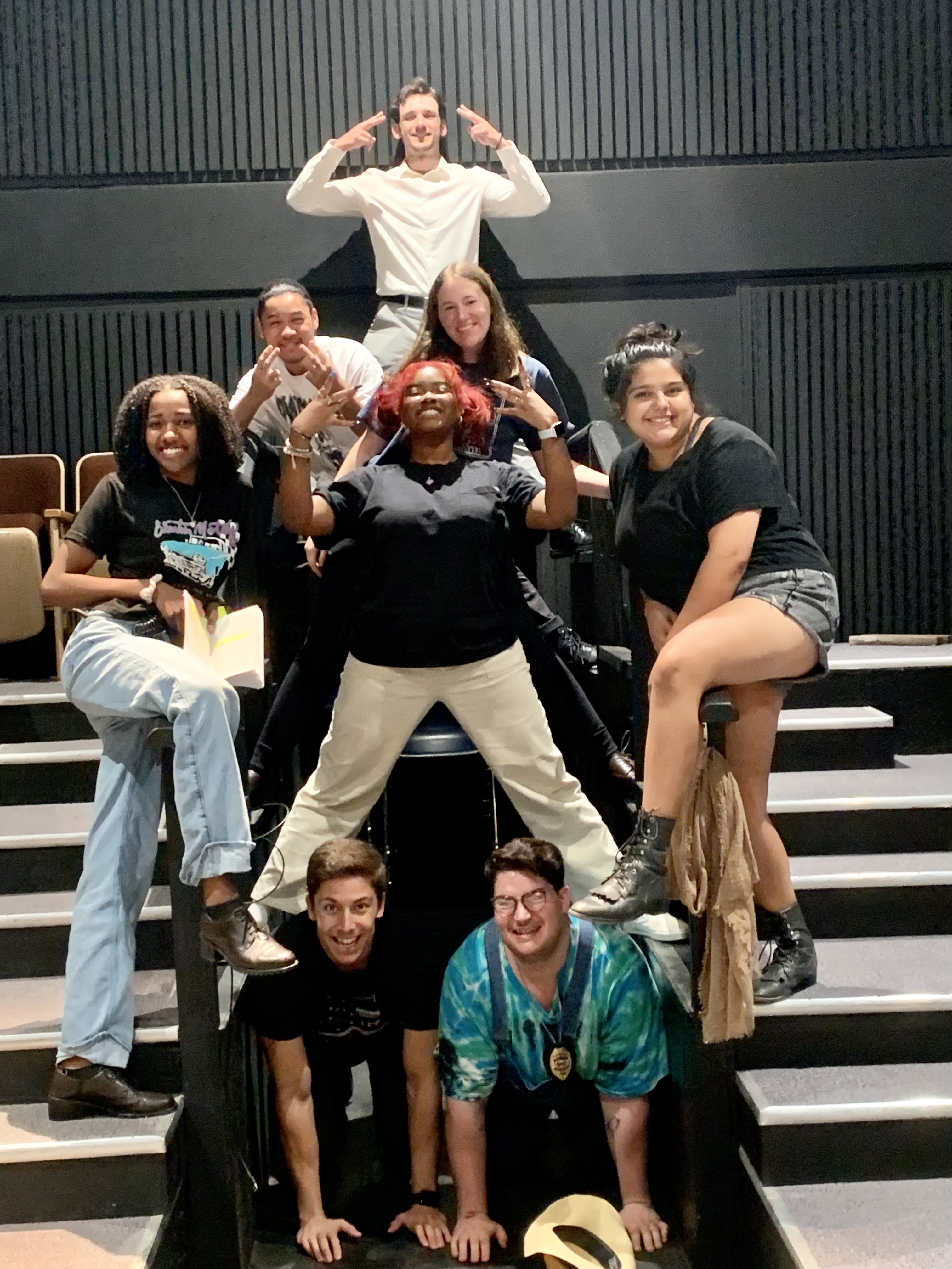 Eight actors posing for a photo on a stage